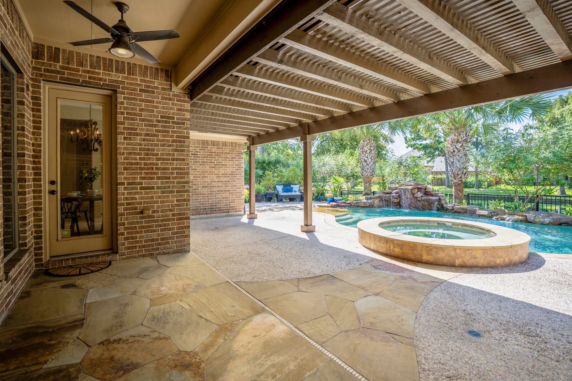 2407 Hendricks Lakes Drive, Spring, TX 77388 Beneath the 30 covered pergola, the patio becomes an outdoor room made for more than sunny afternoons, with stone underfoot, support columns, and shade stretching across the back of the home. The raised spa sits just beyond the covered area, keeping the pool and water-view setting close while giving this part of the backyard a relaxed, lounge-like feel.