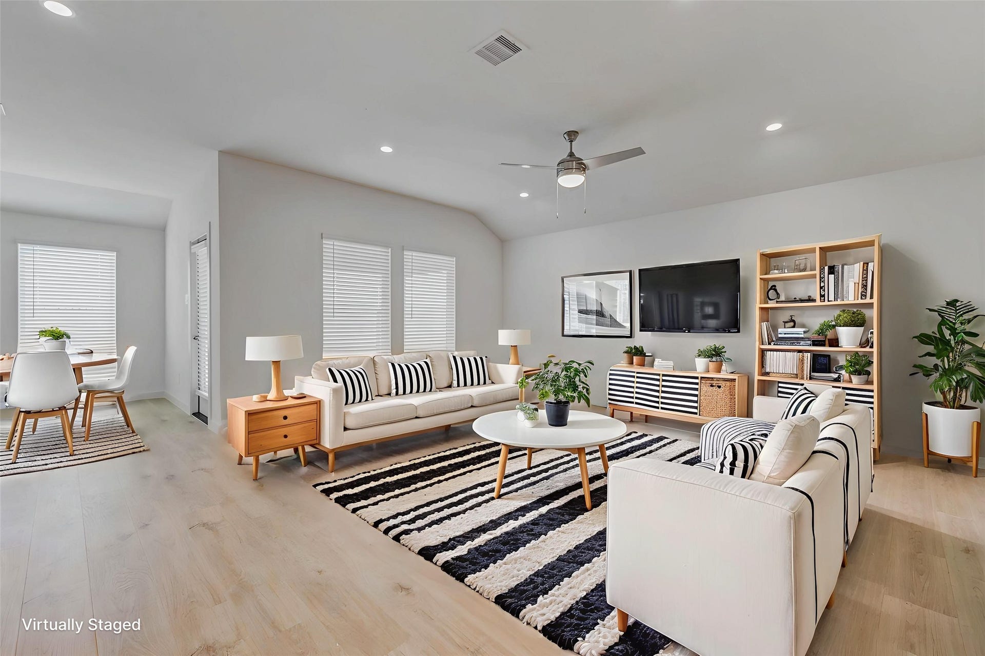 30307 Lighthouse Bluff Lane, Fulshear, TX 77441 Virtually staged. This photo showcases a modern, open-concept living and dining area with light wood flooring and neutral walls. The dining area is cozy and well-lit with natural light.