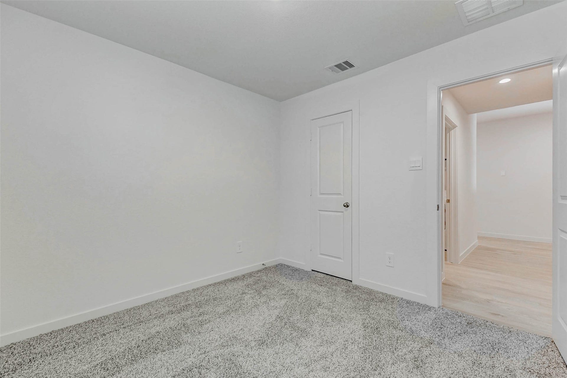 30307 Lighthouse Bluff Lane, Fulshear, TX 77441 This room features neutral-colored walls and carpet flooring, providing a clean and cozy space. It has a simple design with a white door leading to a hallway with hardwood floors. Perfect for a bedroom or office.