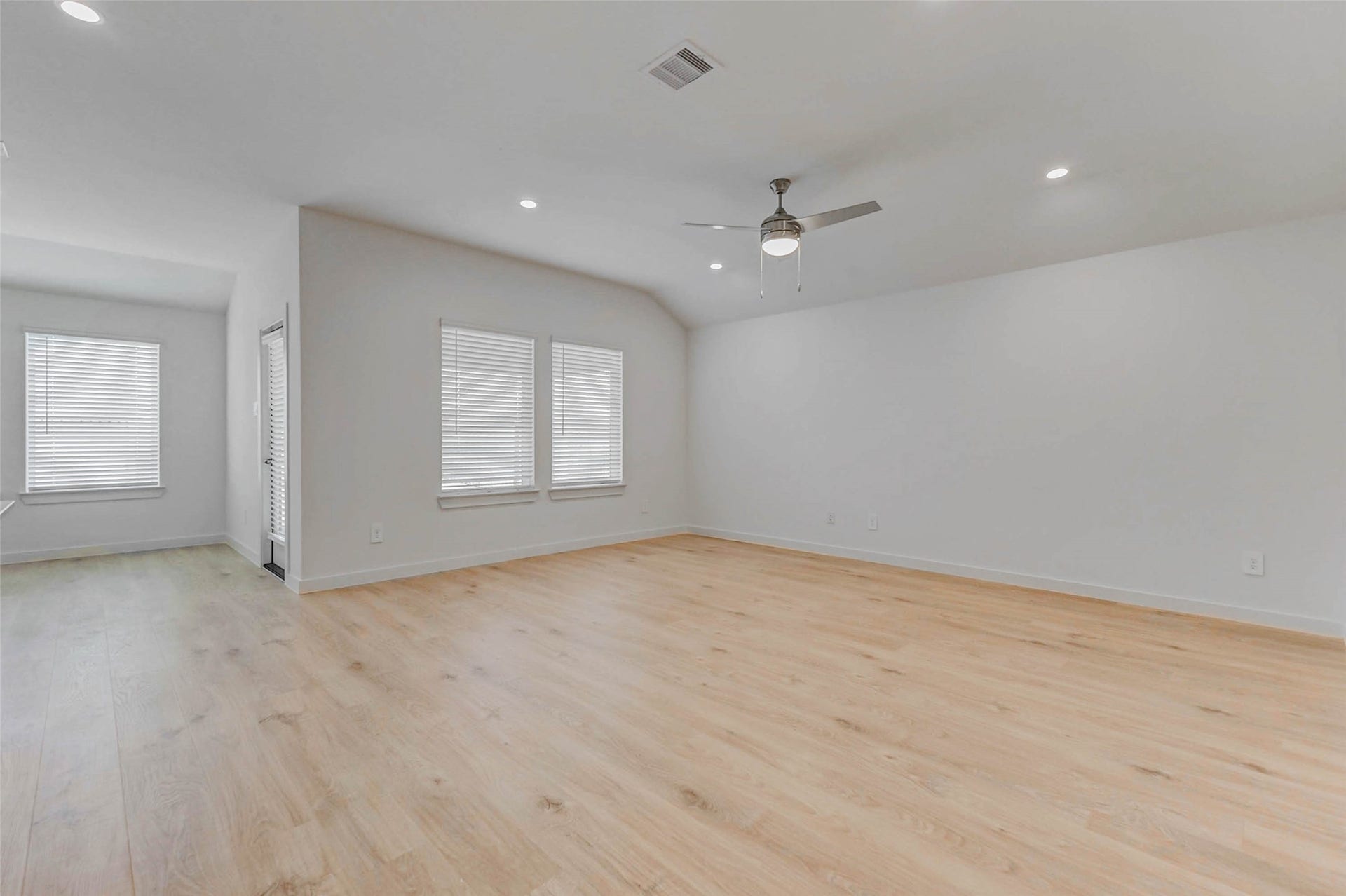 30307 Lighthouse Bluff Lane, Fulshear, TX 77441 Bright and spacious living area with light wood flooring, neutral walls, recessed lighting, and a ceiling fan. The room features large windows for natural light and an open layout, ideal for versatile furnishing.