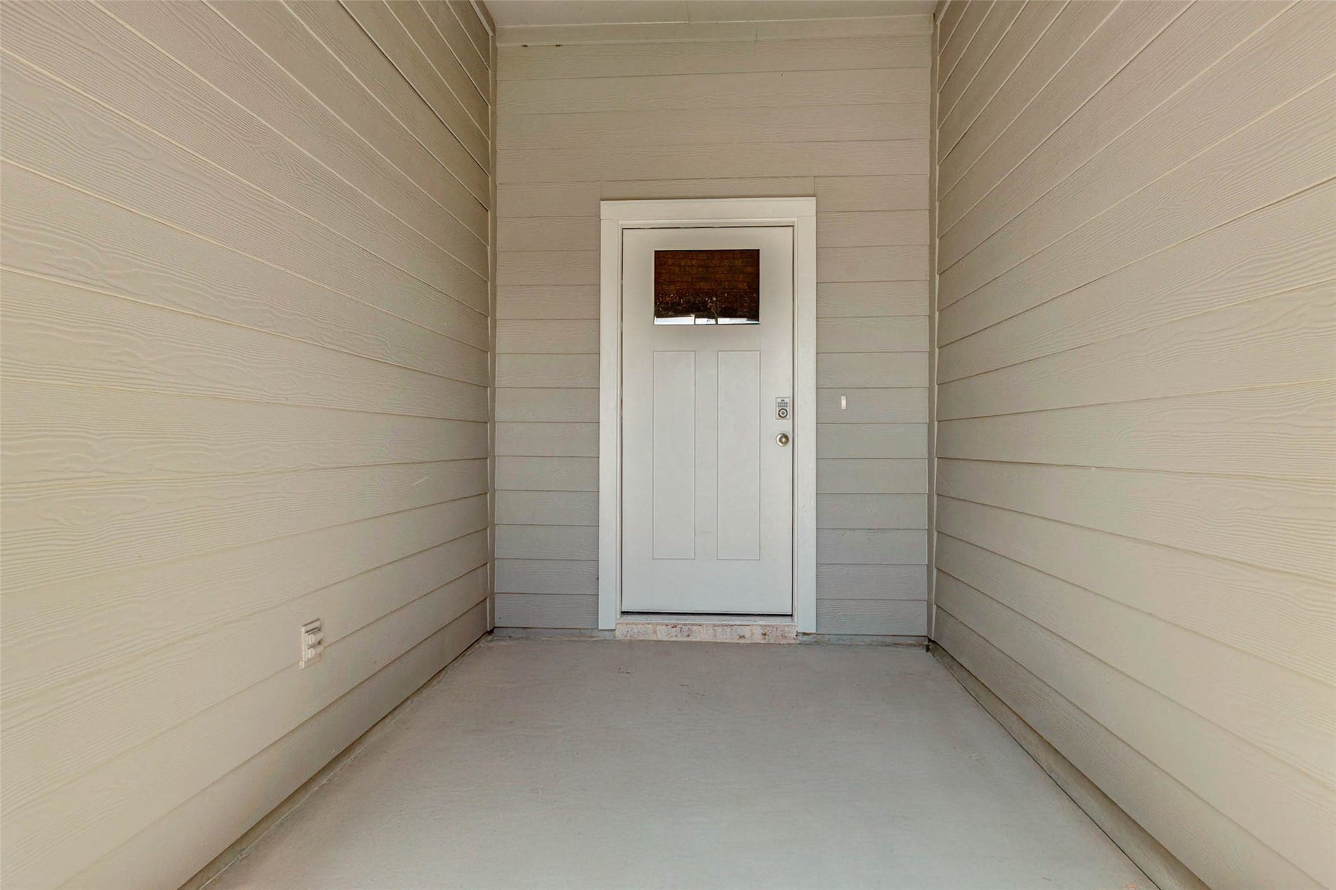 30307 Lighthouse Bluff Lane, Fulshear, TX 77441 Covered entryway with siding and a modern white front door. The space is clean and inviting, offering a welcoming entrance to the home.