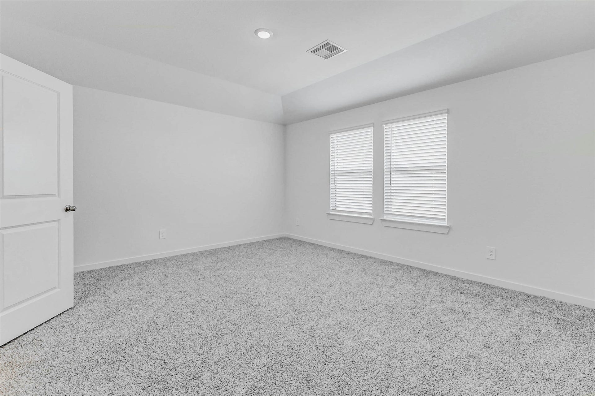 30307 Lighthouse Bluff Lane, Fulshear, TX 77441 This photo depicts a bright, carpeted bedroom with neutral walls, recessed lighting, and two windows with blinds, creating a clean and inviting space.