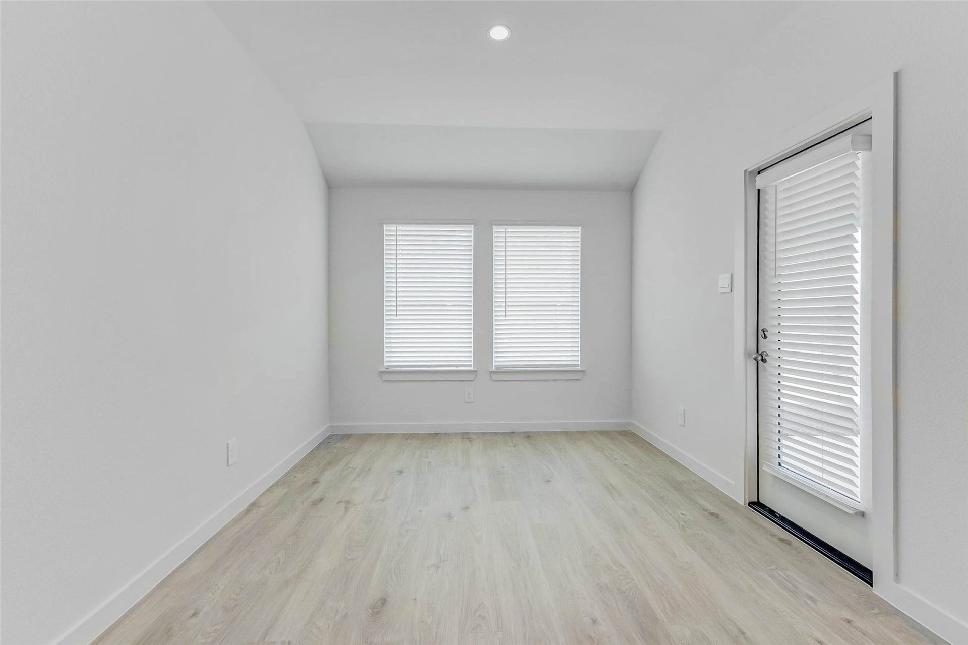30307 Lighthouse Bluff Lane, Fulshear, TX 77441 Bright, minimalistic room with light wood flooring and white walls. Features two large windows with blinds and a glass door, allowing ample natural light. Ideal for a small office or reading nook.
