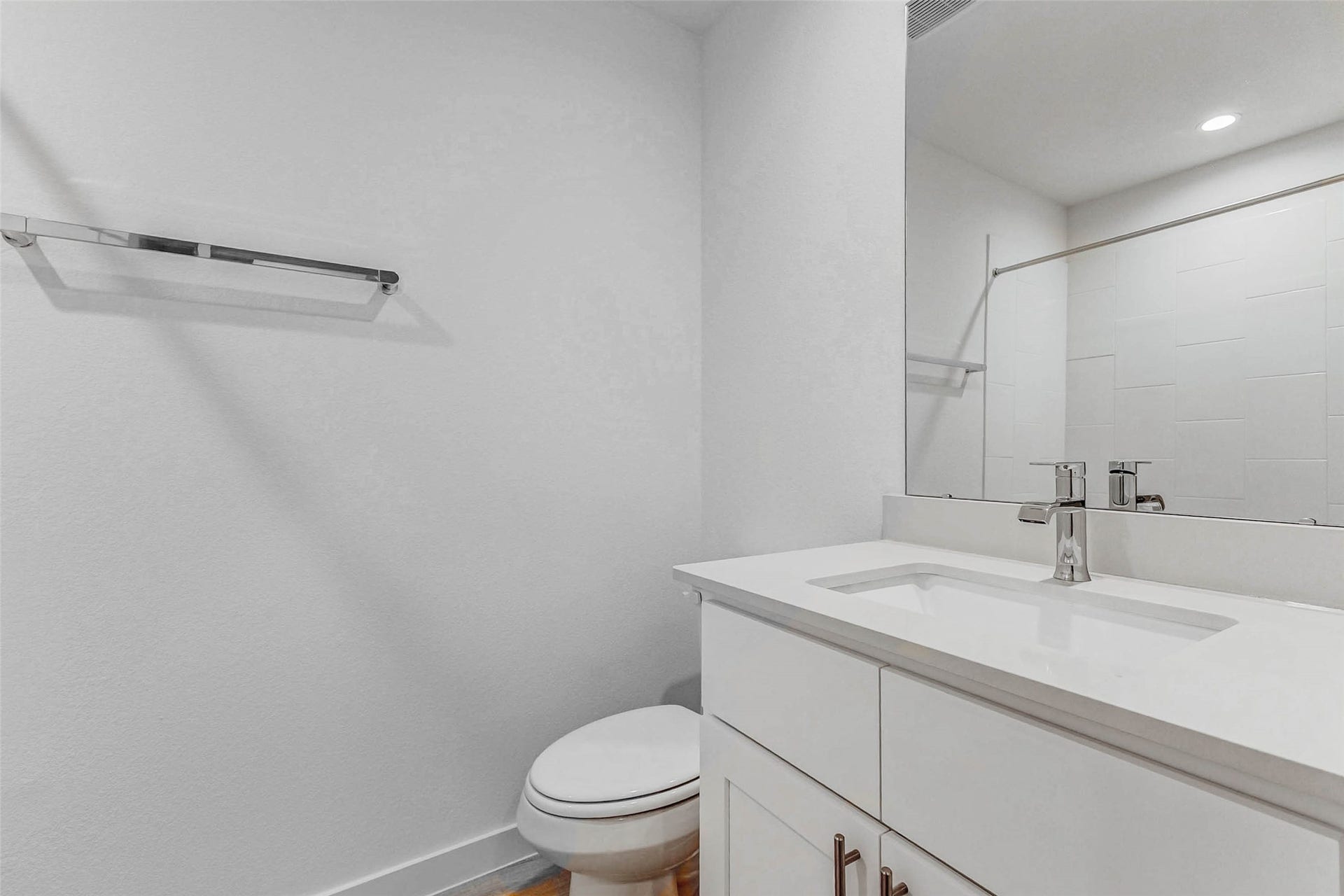 30307 Lighthouse Bluff Lane, Fulshear, TX 77441 Modern bathroom with a sleek white vanity, a contemporary faucet, a large mirror, and a towel bar. The space has a clean, minimalist design with bright lighting.