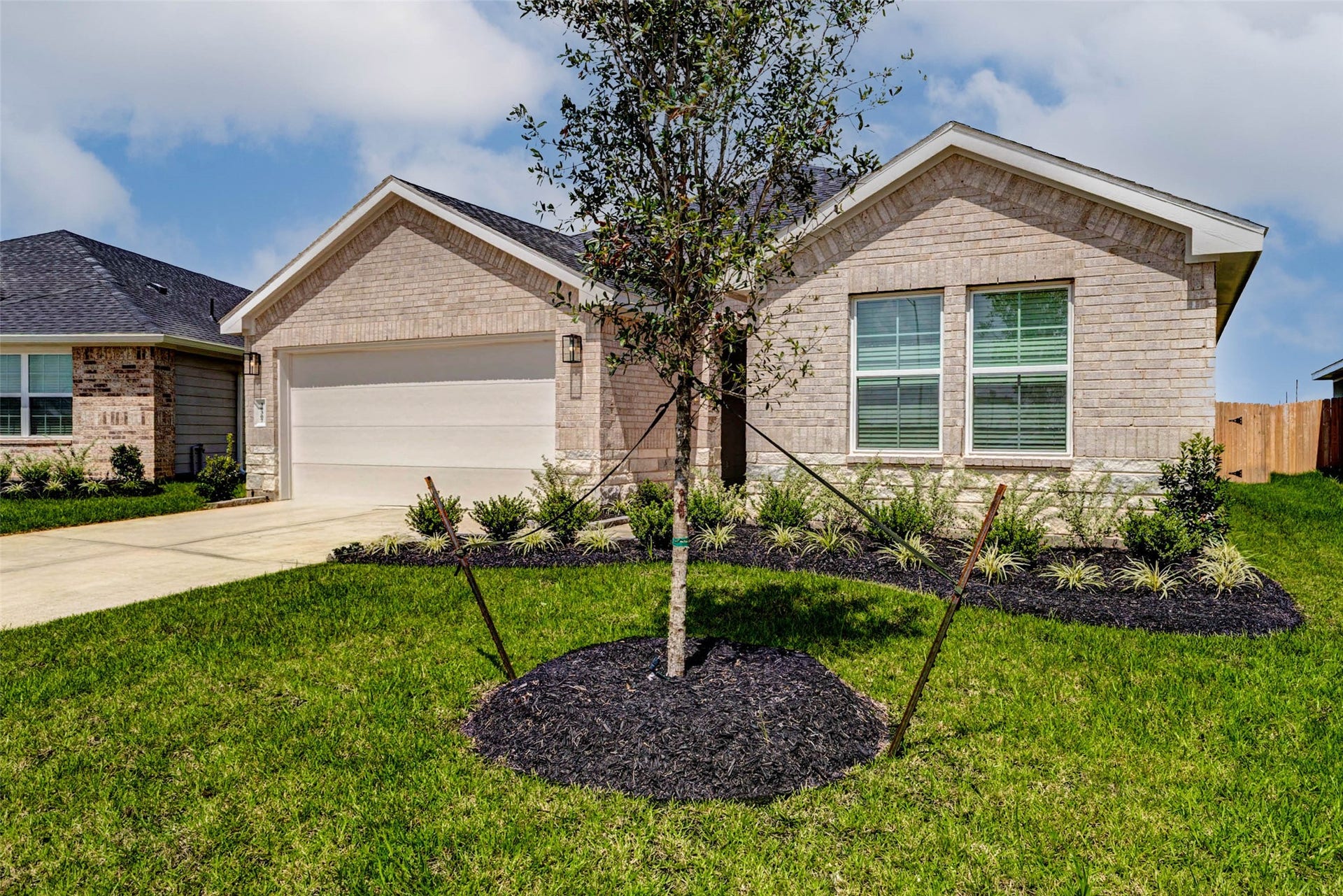 30307 Lighthouse Bluff Lane, Fulshear, TX 77441 This is a charming single-story home with a brick exterior, featuring a two-car garage and a clean, well-maintained front yard. A small tree and landscaped garden enhance its curb appeal.