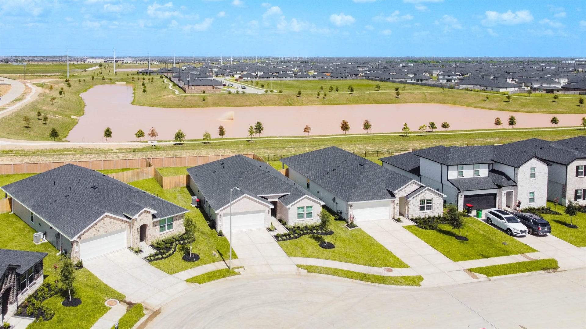 30307 Lighthouse Bluff Lane, Fulshear, TX 77441 Newly built homes in a suburban neighborhood with well-maintained lawns. Located near a large lake, offering scenic views.