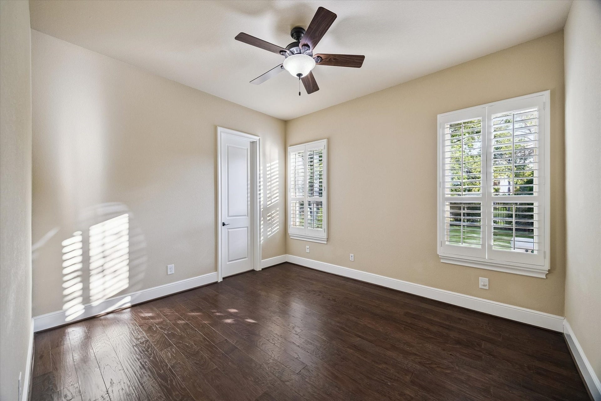 Privately situated on the first floor, this inviting guest suite features hardwood flooring, plantation shutters, a walk-in closet, and a private en-suite bath, offering comfort and convenience for overnight guests or extended family.