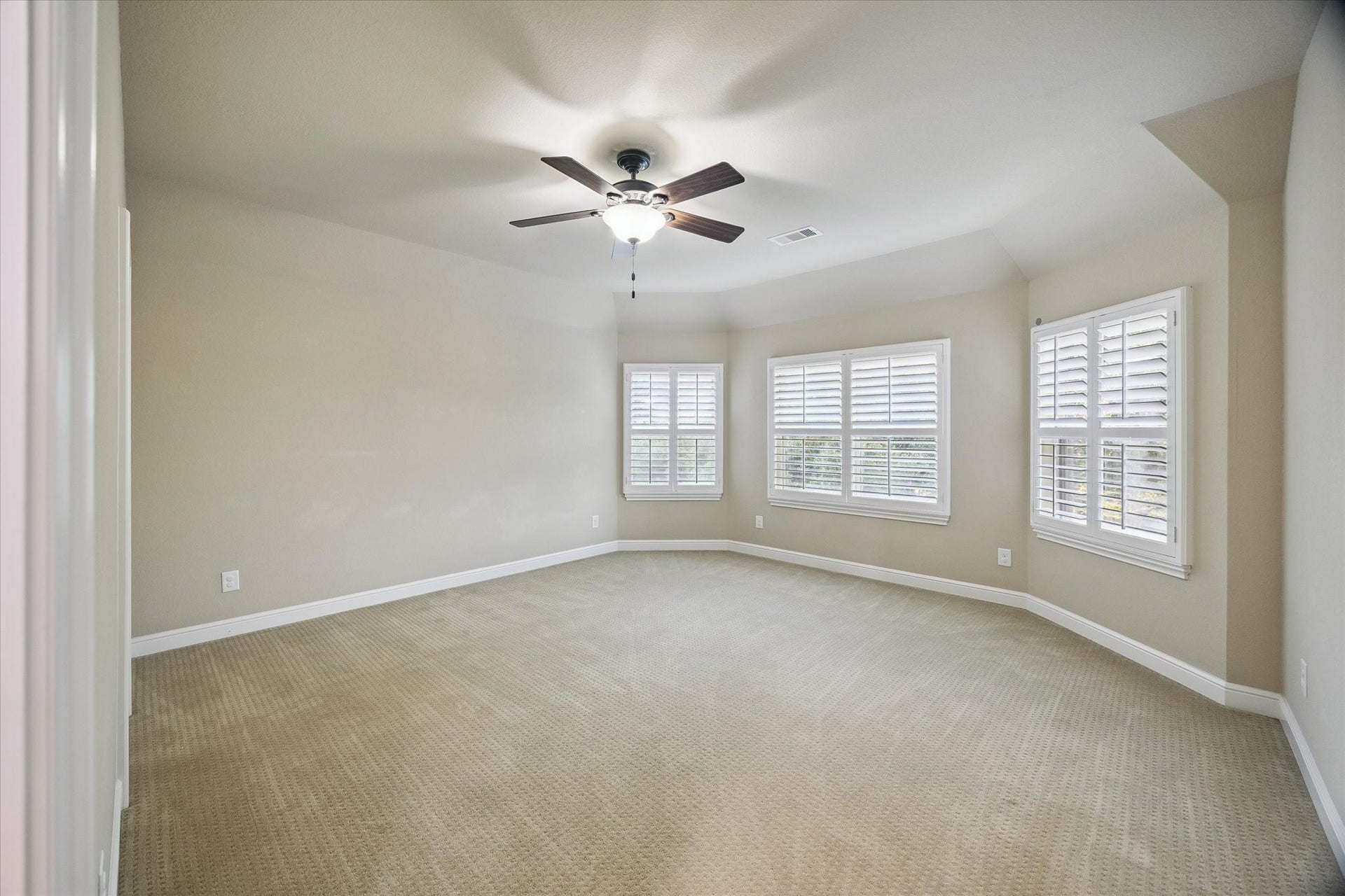 This generously sized secondary bedroom showcases elegant plantation shutters, abundant natural light, and a comfortable layout. A bright and welcoming space that can easily accommodate family, guests, or a personalized retreat.