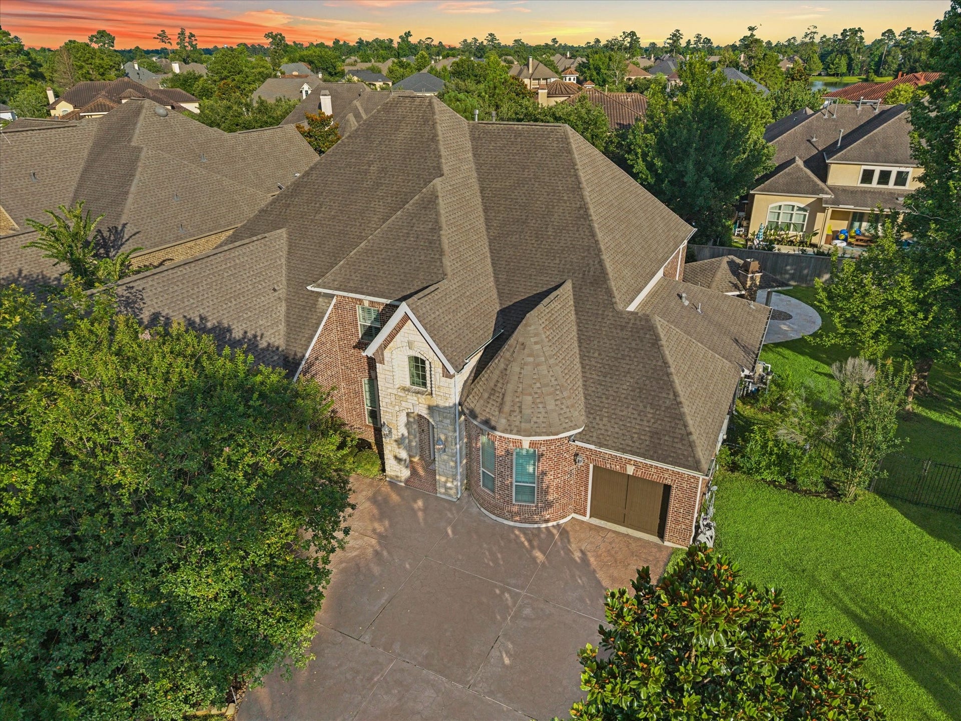 Aerial view showcasing the impressive curb appeal of this distinguished residence, featuring a spacious driveway, stately architecture, mature landscaping, and a beautifully positioned homesite within one of The Woodlands most sought-after communities.