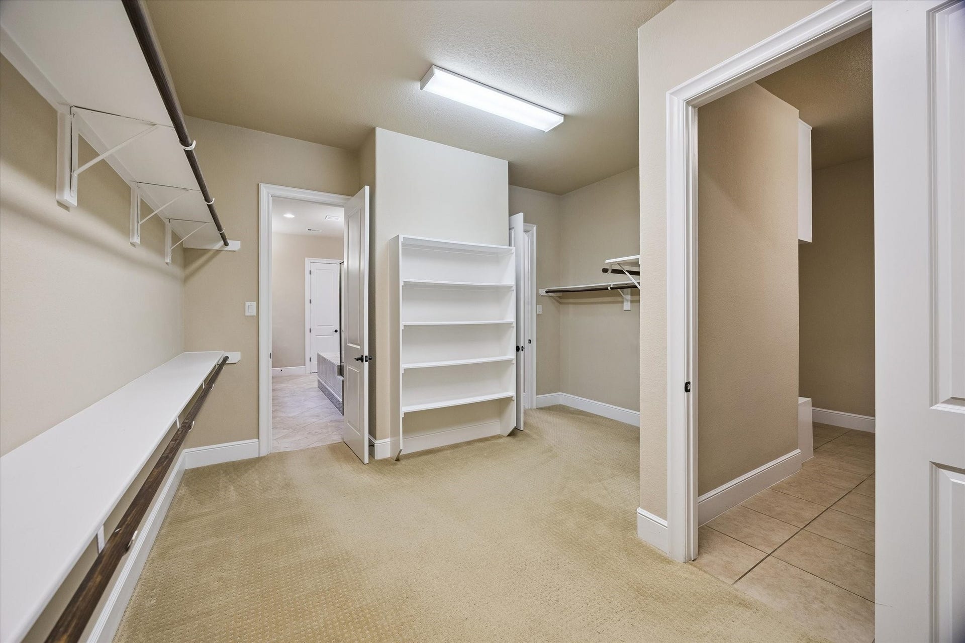 The impressive primary walk-in closet provides exceptional storage with generous hanging space, built-in shelving, and a thoughtfully designed layout. Conveniently positioned between the primary bath and laundry room, it offers both luxury and everyday practicality.