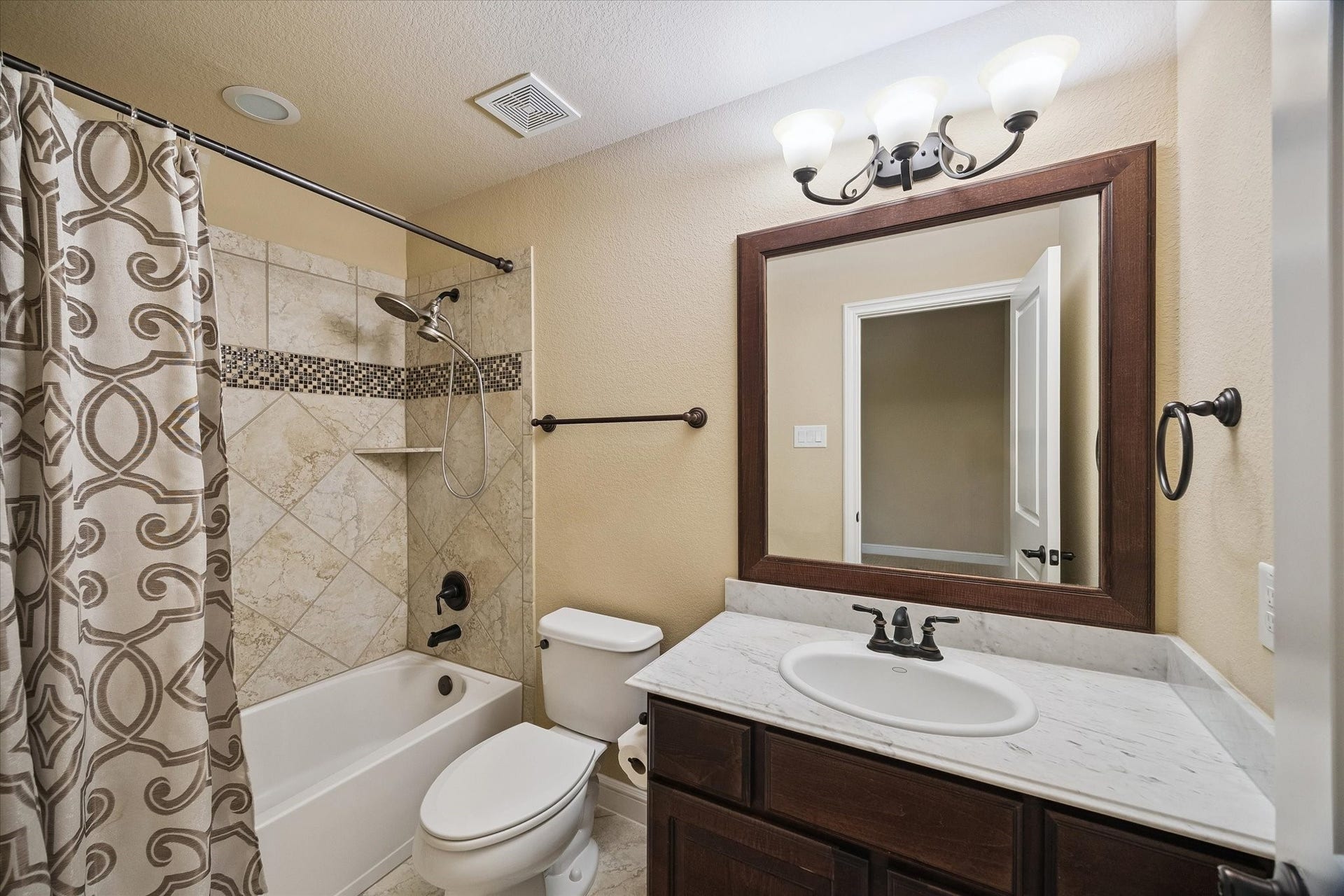 This well-appointed secondary bathroom features a vanity with stone countertops, a tub/shower combination, and tasteful finishes, providing comfort and convenience for the adjoining bedroom.