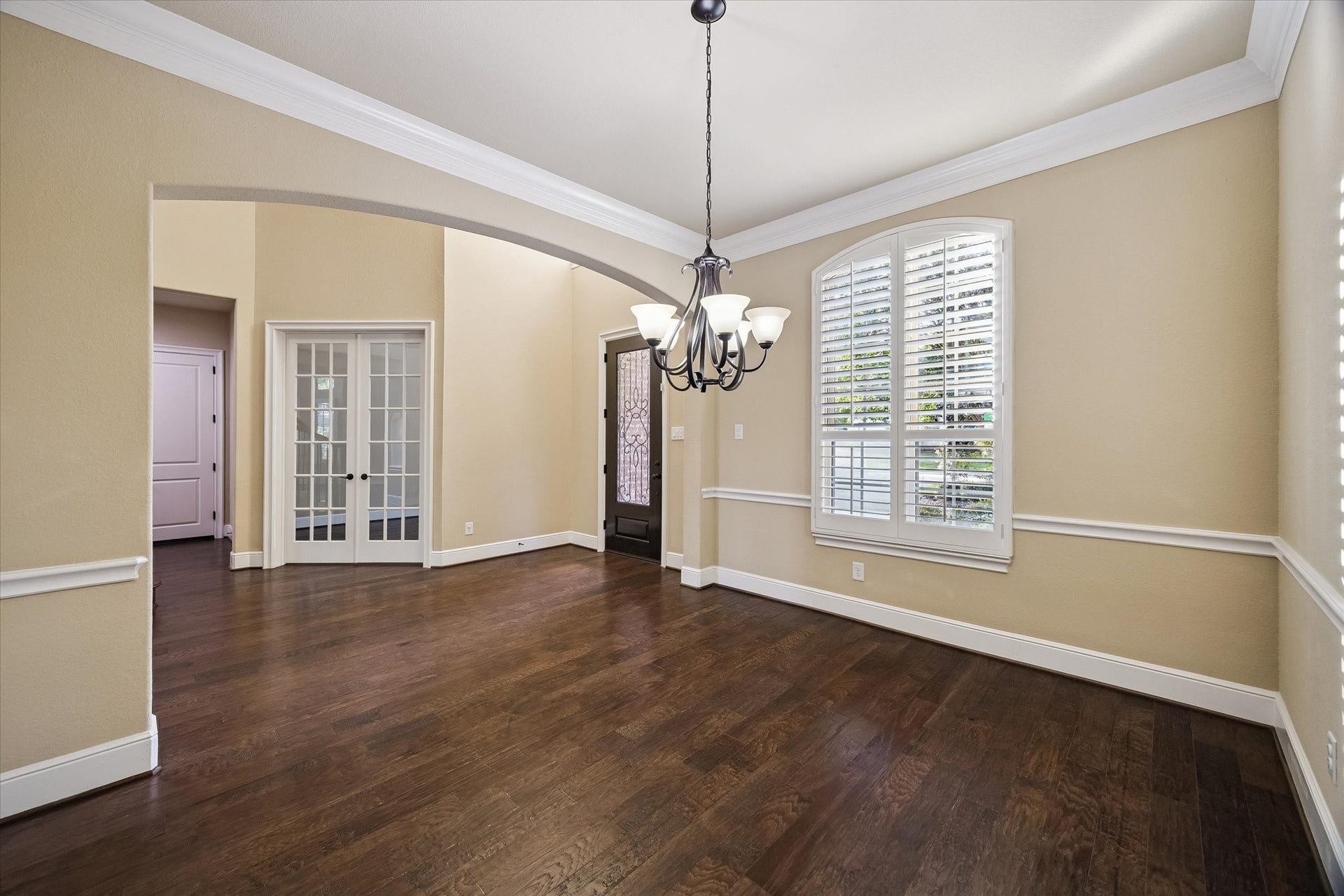 Designed for memorable gatherings, the formal dining room showcases rich hardwood floors, elegant crown molding, plantation shutters, and a warm, welcoming ambiance filled with natural light.