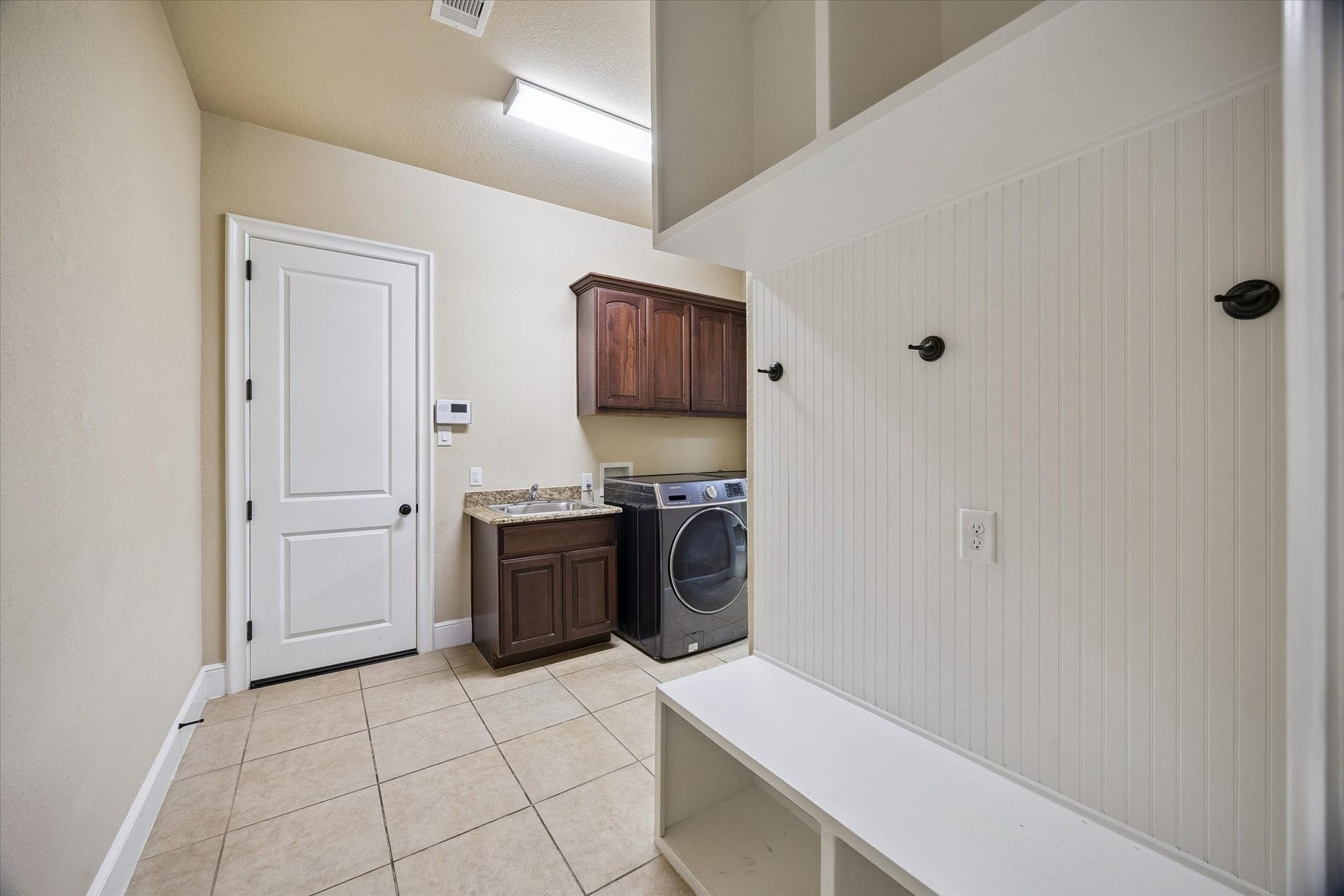 Blending functionality with convenience, the well-appointed laundry and mudroom area features a utility sink, built-in cabinetry, bench seating, and storage hooks. Conveniently positioned between the garage and the primary suite, it helps keep daily life organized and efficient.