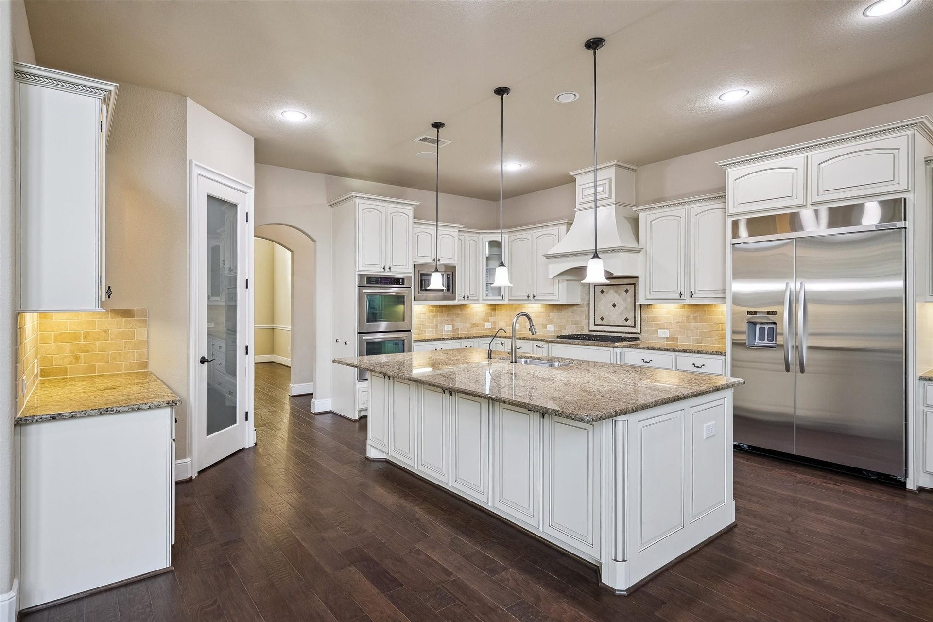 Thoughtfully designed for both everyday living and entertaining, the kitchen features an oversized center island, extensive cabinetry, granite countertops, premium stainless steel appliances, a generously sized refrigerator, and exceptional storage and preparation space.