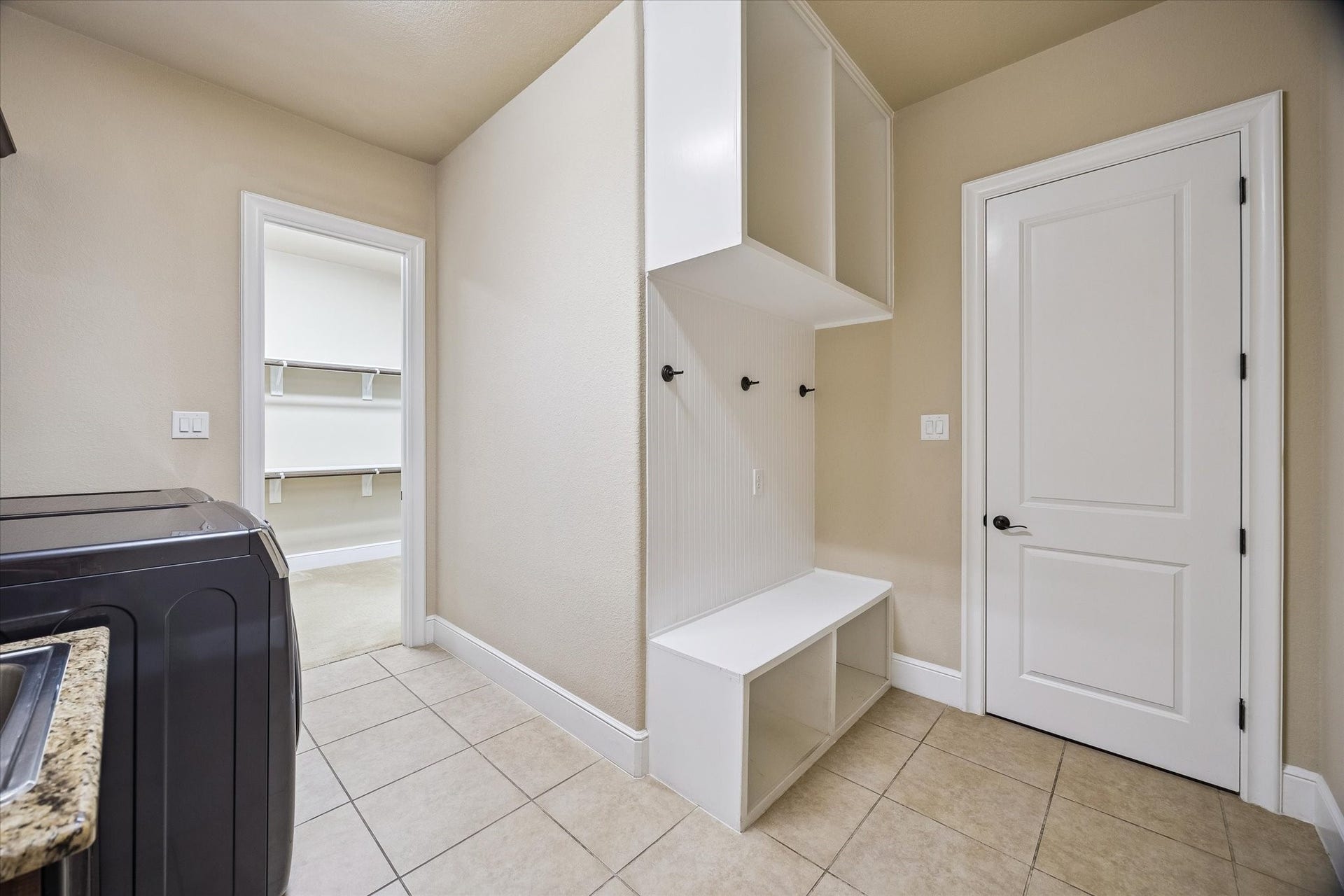 Enhancing everyday convenience, the mudroom and laundry area features built-in storage, bench seating, and direct access to the primary closetan intelligent design feature that promotes organization and efficiency.