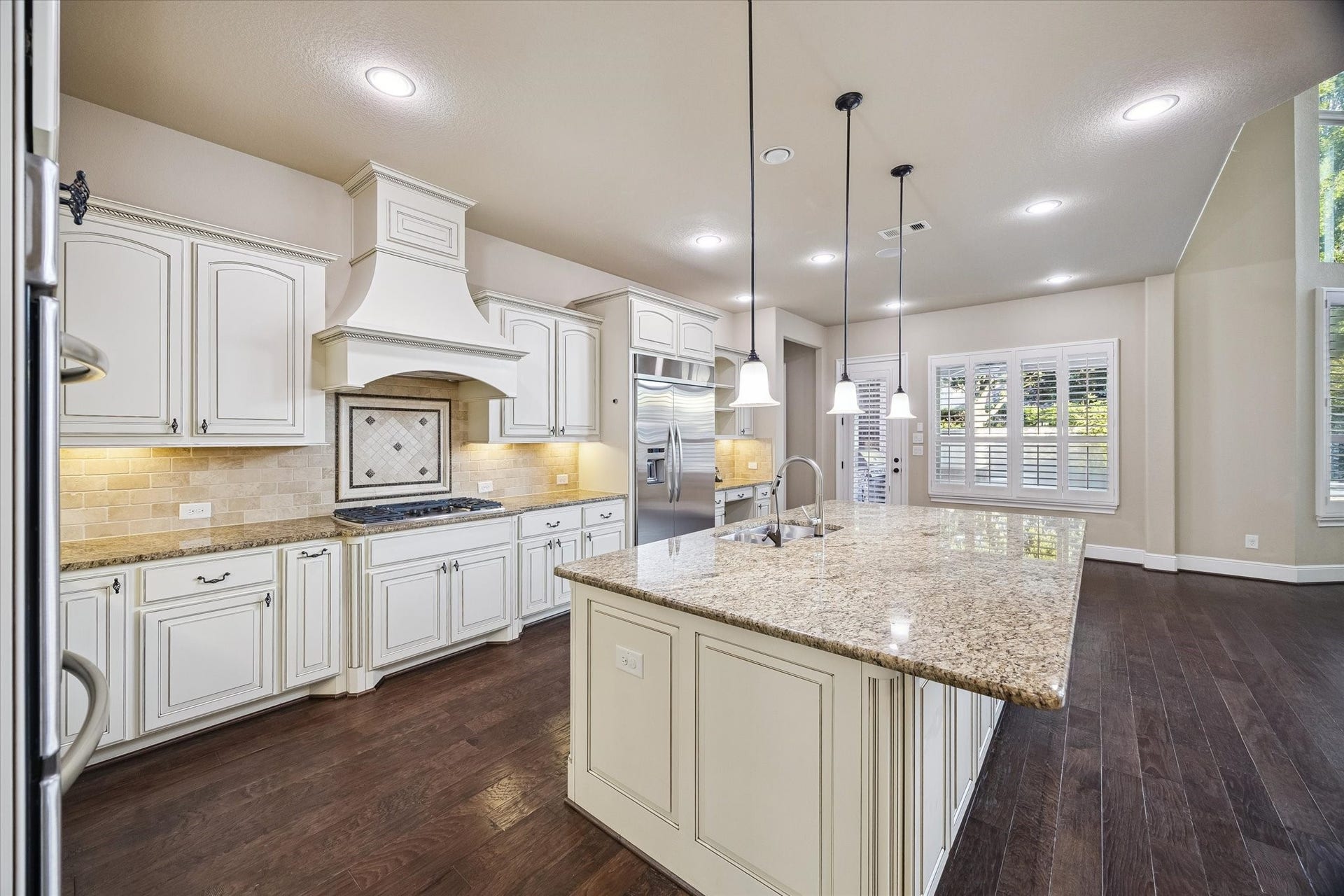 Designed for both everyday living and entertaining, the kitchen features an oversized island with seating, extensive cabinetry, abundant workspace, and a light-filled breakfast area. A thoughtfully designed built-in workstation offers a convenient space for meal planning, studying, or working from home while remaining at the center of the home's activity.
