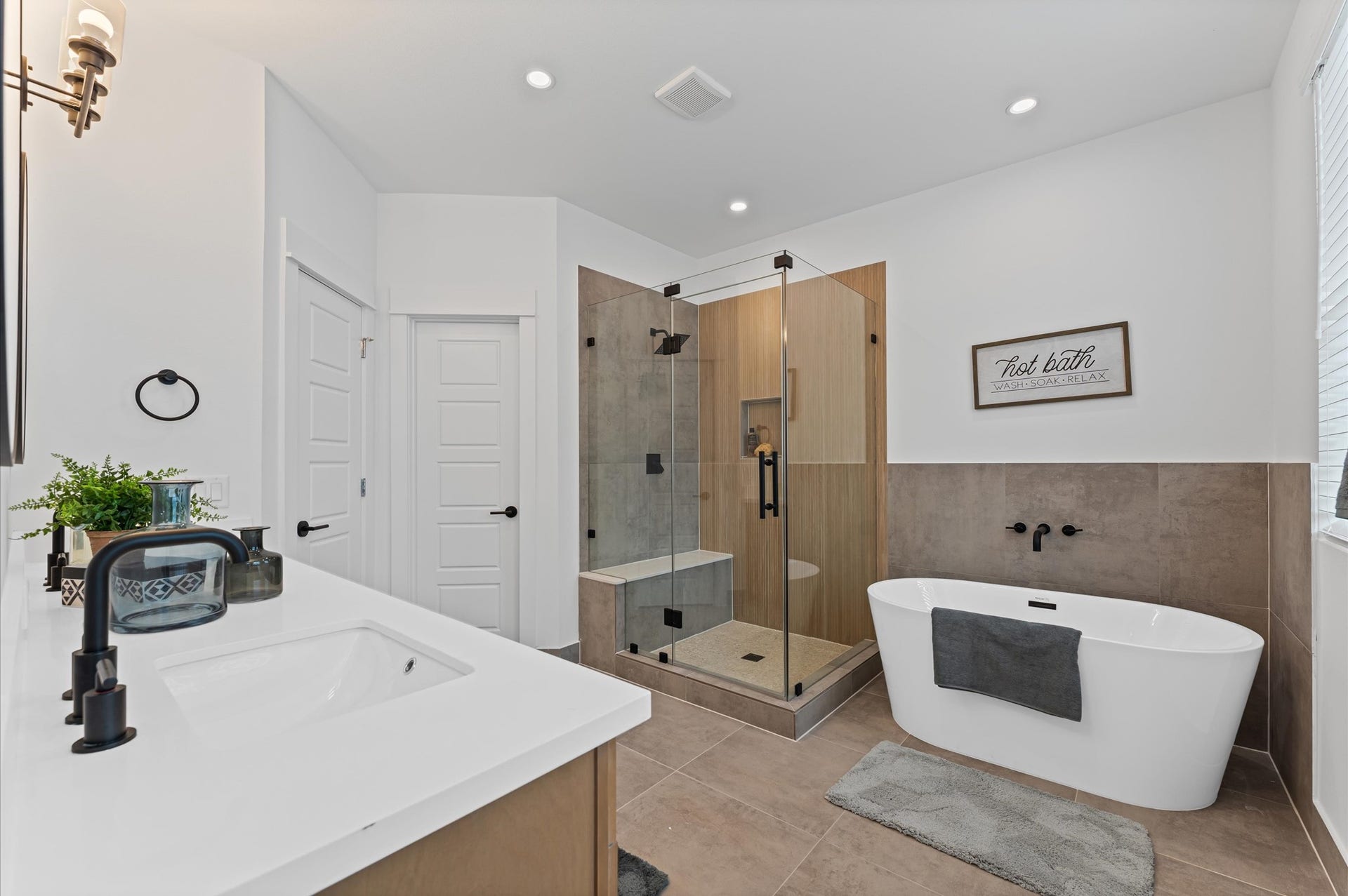 412 Neyland Street, #G, Houston, TX 77022 This luxurious primary bathroom blends modern elegance with spa-like comfort, featuring a spacious layout and contemporary selections throughout. A sleek double vanity with minimalist cabinetry and quartz countertops offers ample storage and style, while the glass-enclosed shower includes a built-in bench for added relaxation and convenience. The centerpiece is a sculptural freestanding soaking tub, perfectly positioned to invite unwinding after a long day.