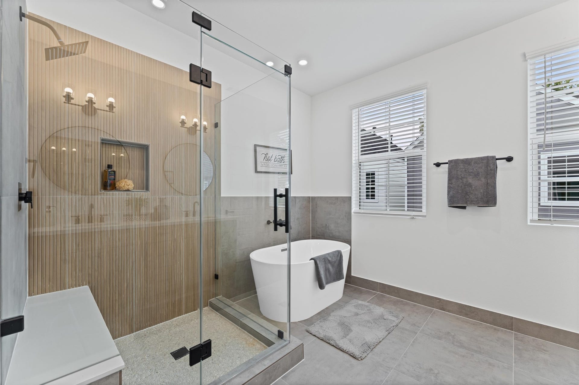 412 Neyland Street, #G, Houston, TX 77022 This luxurious primary bathroom blends modern elegance with spa-like comfort, featuring a spacious layout and contemporary selections throughout. A sleek double vanity with minimalist cabinetry and quartz countertops offers ample storage and style, while the glass-enclosed shower includes a built-in bench for added relaxation and convenience. The centerpiece is a sculptural freestanding soaking tub, perfectly positioned to invite unwinding after a long day.