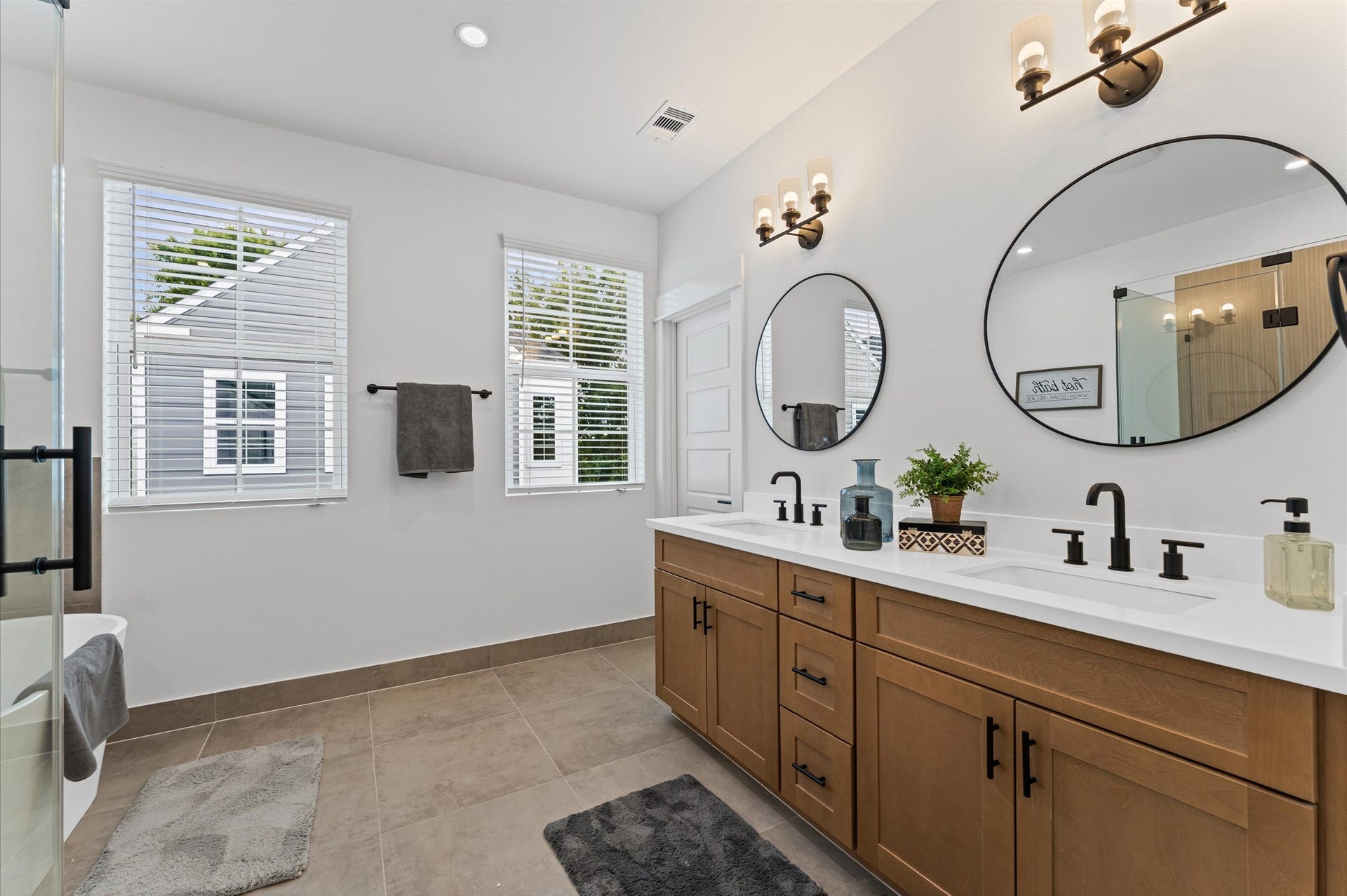 412 Neyland Street, #G, Houston, TX 77022 This luxurious primary bathroom blends modern elegance with spa-like comfort, featuring a spacious layout and contemporary selections throughout. A sleek double vanity with minimalist cabinetry and quartz countertops offers ample storage and style, while the glass-enclosed shower includes a built-in bench for added relaxation and convenience. The centerpiece is a sculptural freestanding soaking tub, perfectly positioned to invite unwinding after a long day.