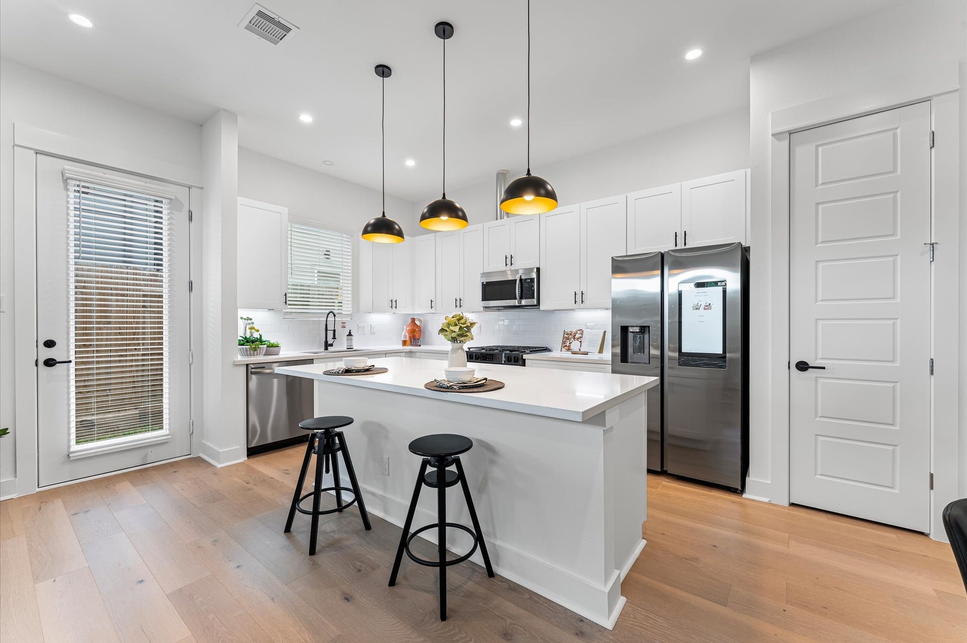 412 Neyland Street, #G, Houston, TX 77022 This centrally positioned kitchen island serves as a stylish anchor within the open-concept layout, offering clear sightlines to the dining area, living space, and the backyard beyond. Its placement encourages seamless interaction, whether prepping meals or entertaining guests, while natural light pours in through the nearby windows. The islands sleek design and functional surface make it a hub of activity, framed by elegant finishes tying together comfort and sophistication.