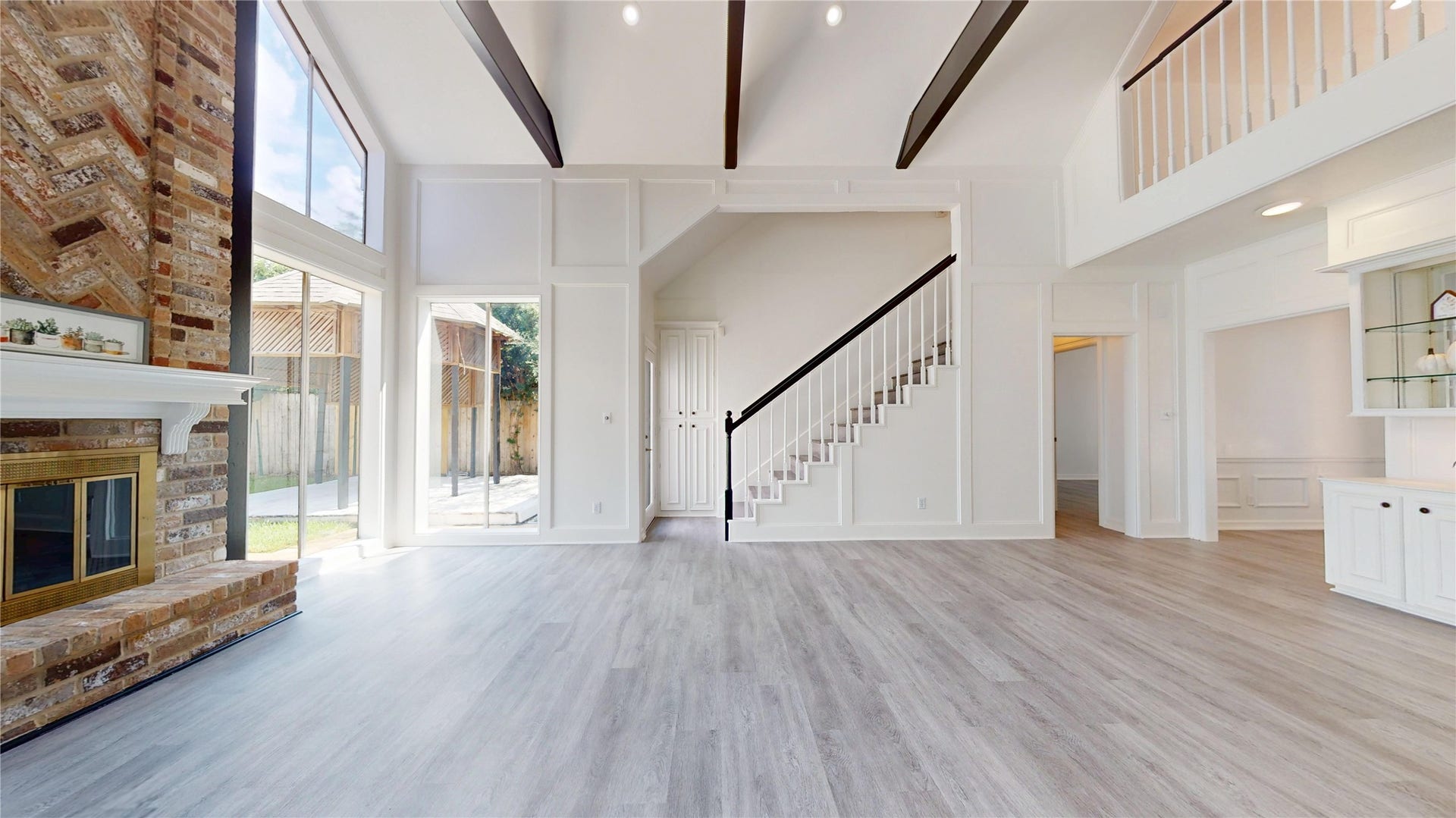 1407 Sherfield Ridge Drive, Katy, TX 77450 1407 Sherfield Ridge Dr, Stunning open concept living room side picture from the breakfast area, with vaulted ceilings exposed dark wood beams, abundant natural light from oversized windows and warm wood laminate flooring. Open staircase with contrasting dark handrail compliments the architectural detail and second floor overlook enhances the open, airy feel of the space.