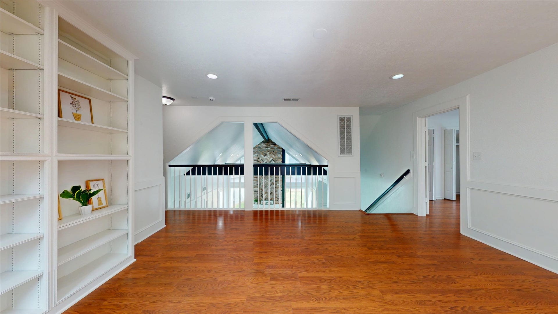 1407 Sherfield Ridge Drive, Katy, TX 77450 1407 Sherfield Ridge Dr, Bright and spacious upstairs living area featuring warm wood flooring, recessed lighting and built-in shelving. Decorative wall molding adds character, while the open railing overlooks the lower level. The versatile space is ideal for a game room, media area, home office, or additional family room.