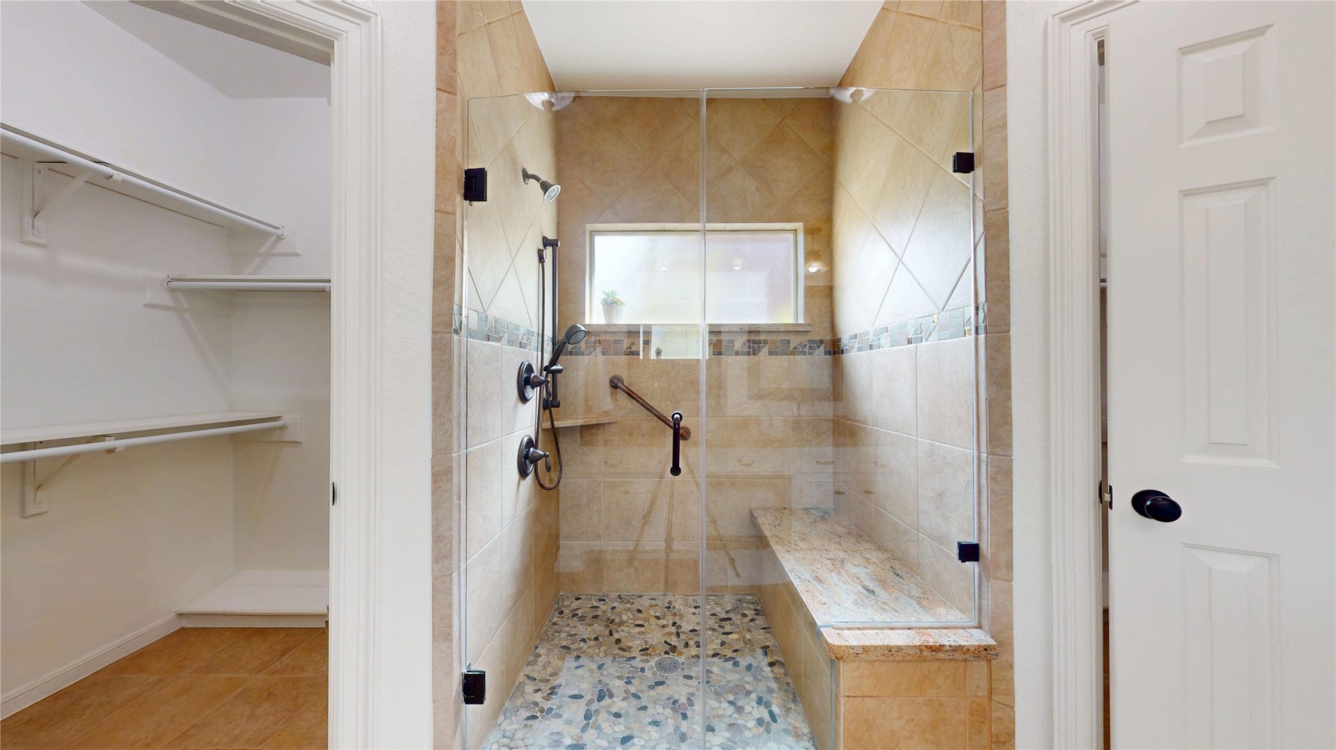1407 Sherfield Ridge Drive, Katy, TX 77450 1407 Sherfield Ridge Dr, Primary bathroom with oversized walk-in shower offers frameless glass doors, tiled walls, built-in shelving, multiple shower fixtures, and a convenient bench. Entrance to large primary walk-in closet.