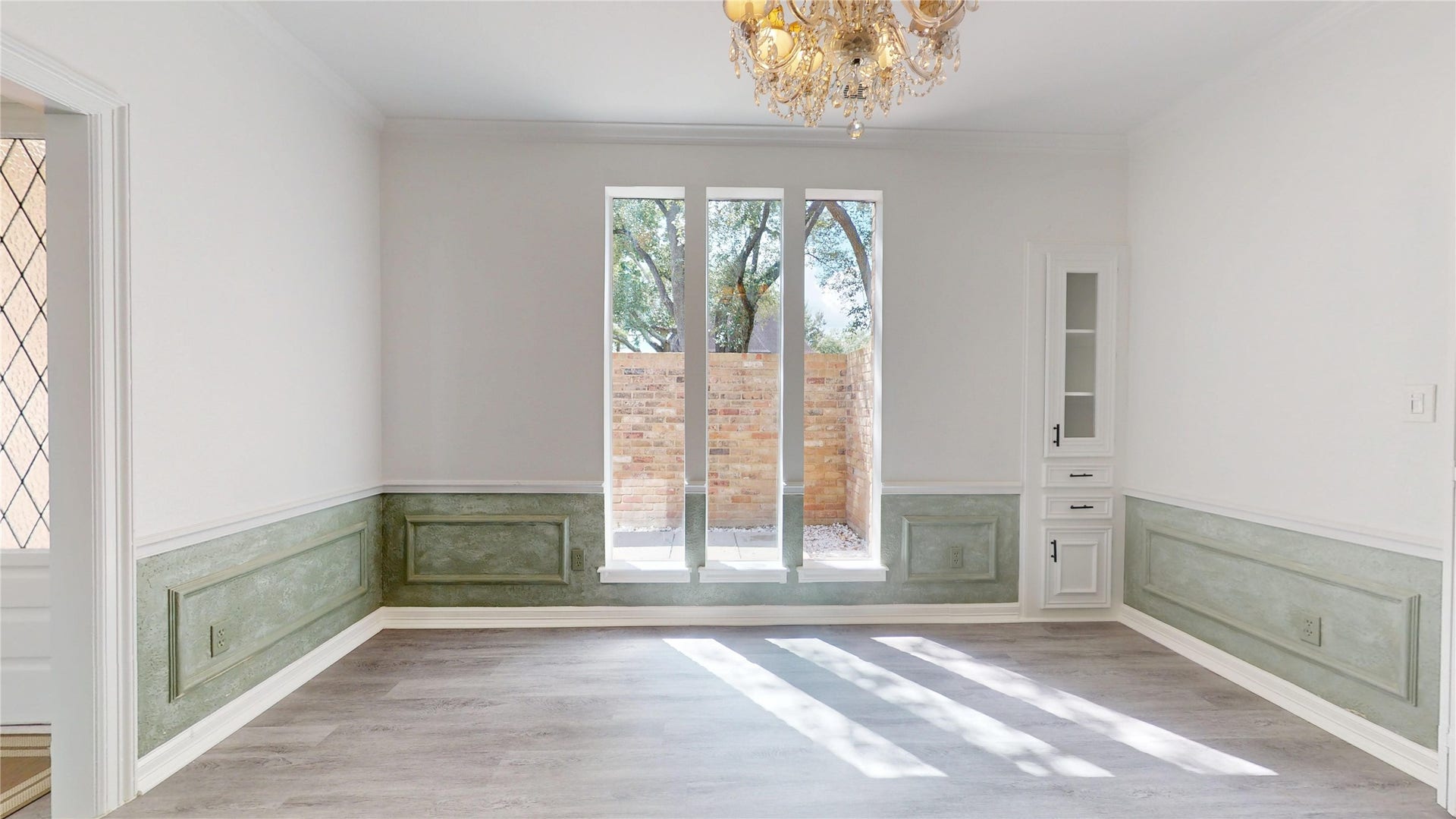 1407 Sherfield Ridge Drive, Katy, TX 77450 1407 Sherfield Ridge Dr, Formal dining area featuring decorative soft sage wainscoting/picture frame wall molding, tall windows that bring in abundant natural light facing the covered in brick patio. The room is accented by a crystal chandelier and built in babinitry and wooden laminate florring throughout.