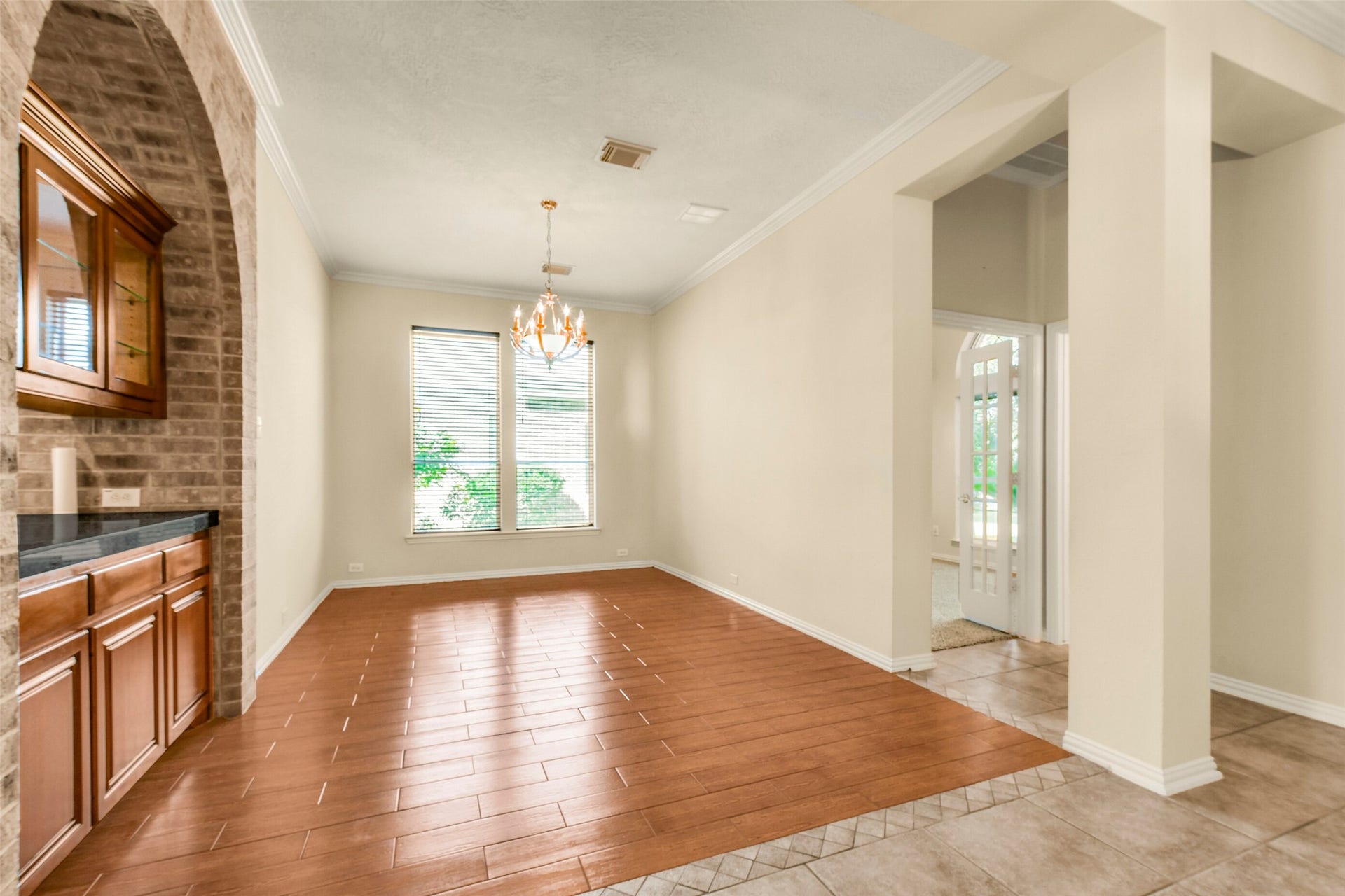 9902 Autumn Lake Trail, Pearland, TX 77584 Elegant dining area with warm wood flooring, a charming chandelier, and ample natural light from large windows. Brick accent and built-in cabinetry add a touch of sophistication.