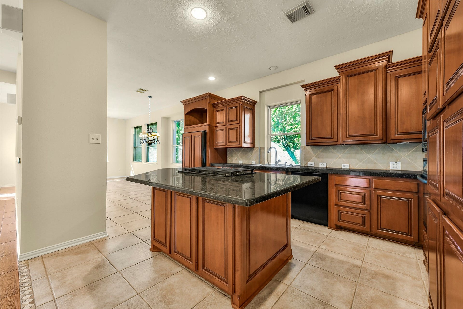 9902 Autumn Lake Trail, Pearland, TX 77584 Spacious kitchen featuring rich wooden cabinetry, a sleek granite island, and a bright breakfast nook overlooking lush greenery.