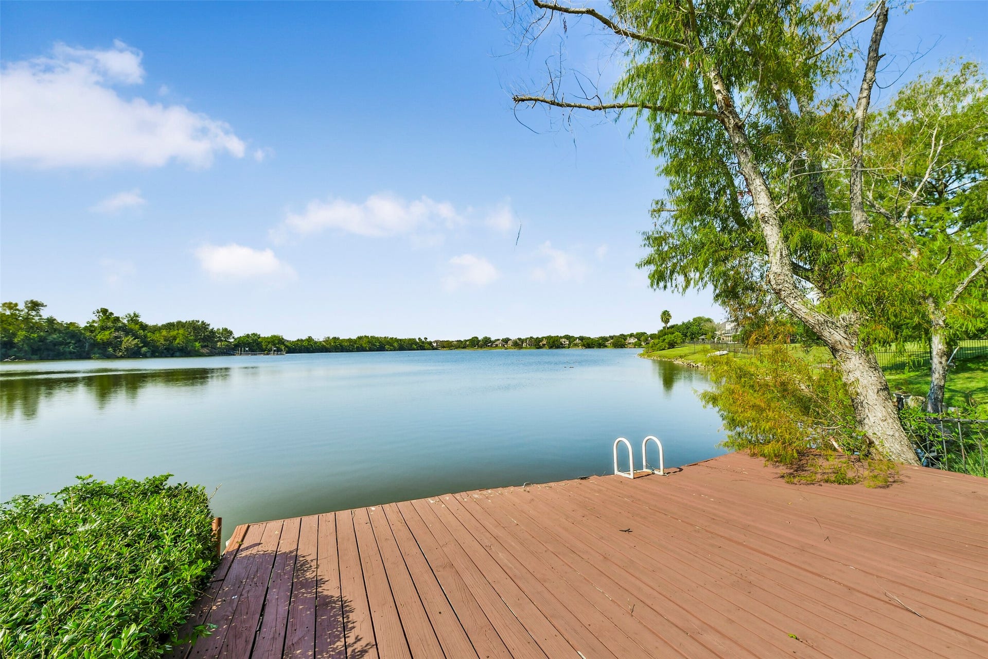 9902 Autumn Lake Trail, Pearland, TX 77584 Tranquil lakefront setting with a spacious wooden deck, perfect for relaxation and enjoying serene water views.