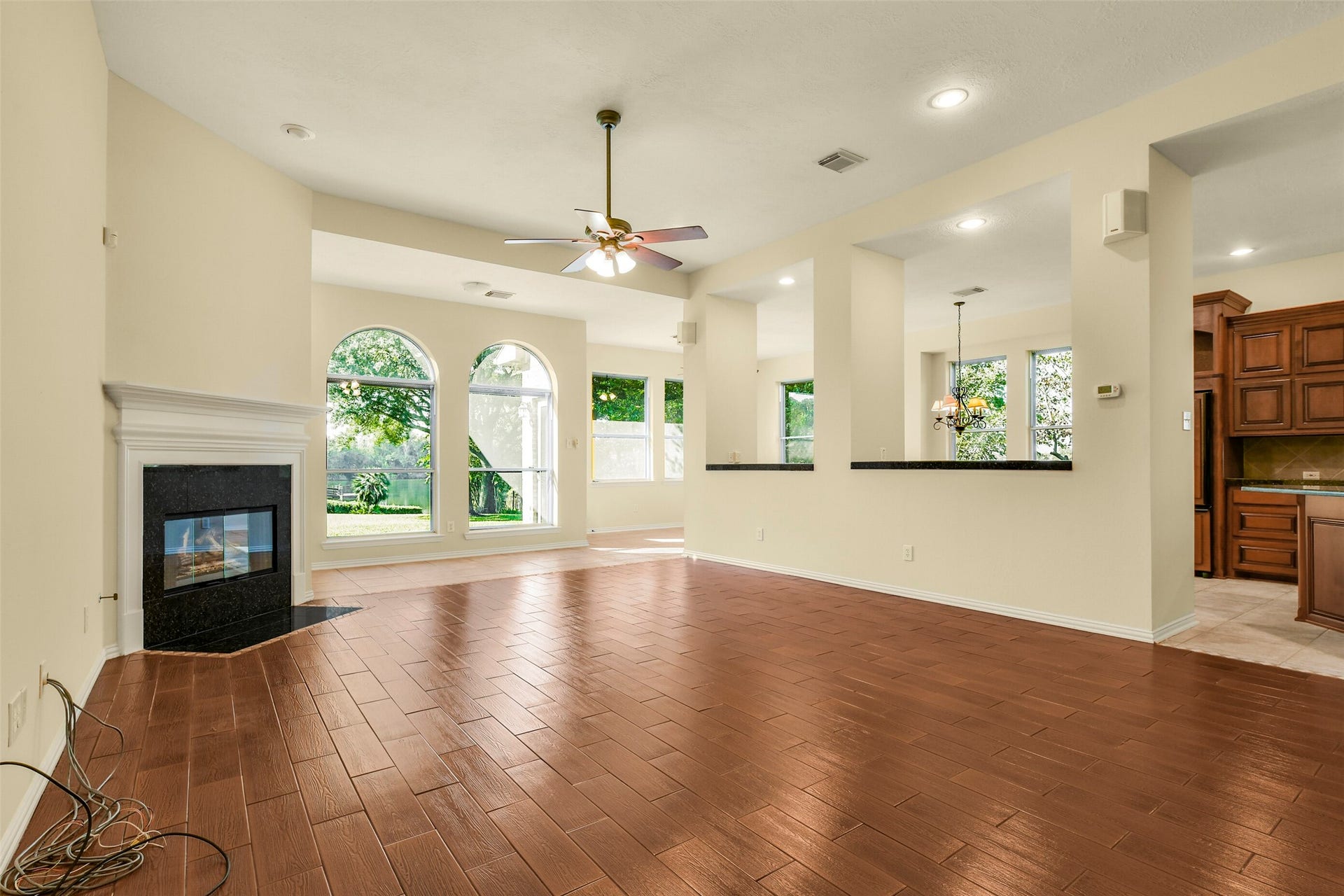 9902 Autumn Lake Trail, Pearland, TX 77584 Spacious living area with elegant wood-look tile flooring, a cozy corner fireplace, and large windows that flood the room with natural light, seamlessly flowing into the dining space and kitchen.