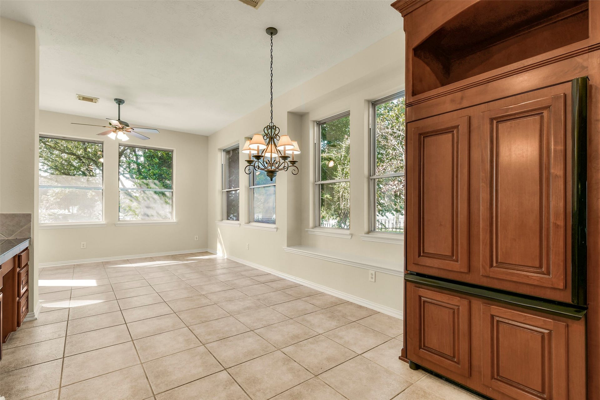 9902 Autumn Lake Trail, Pearland, TX 77584 Bright dining area with large windows, elegant chandelier, and tiled flooring, seamlessly connecting to the kitchen.