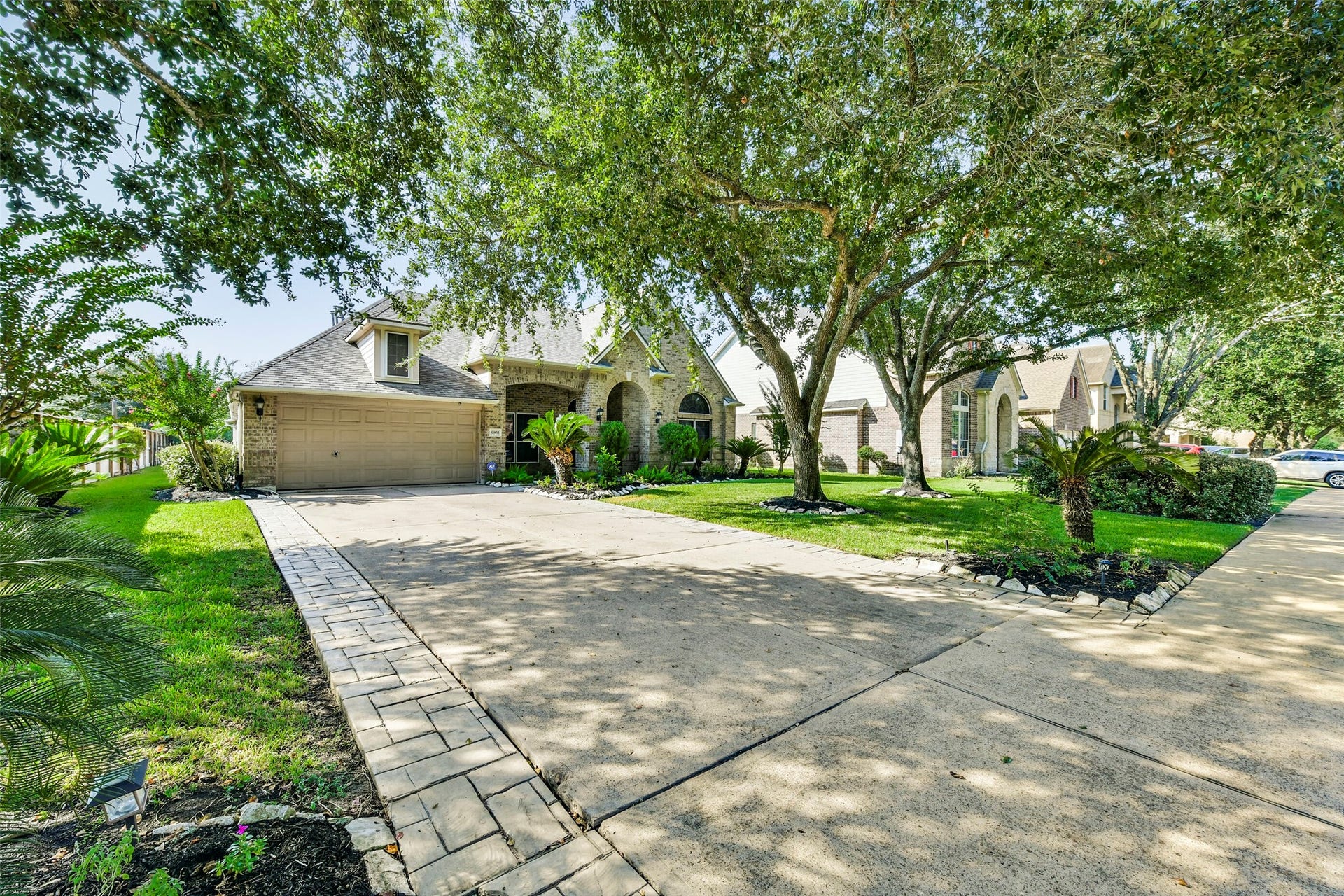 9902 Autumn Lake Trail, Pearland, TX 77584 Charming home with a spacious driveway, lush landscaping, and mature trees offering ample shade and curb appeal.