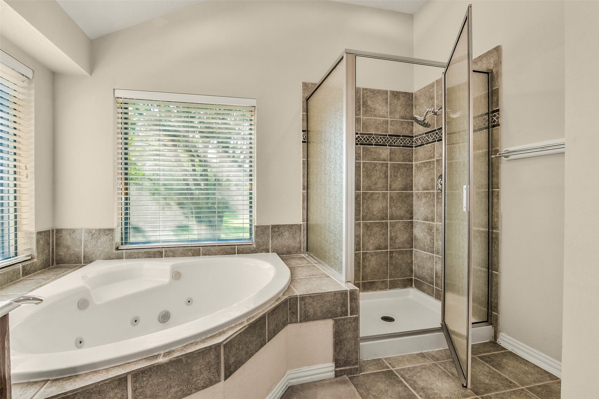 9902 Autumn Lake Trail, Pearland, TX 77584 Luxurious bathroom featuring a spacious jetted tub and a separate tiled shower, accented with natural light from large windows.