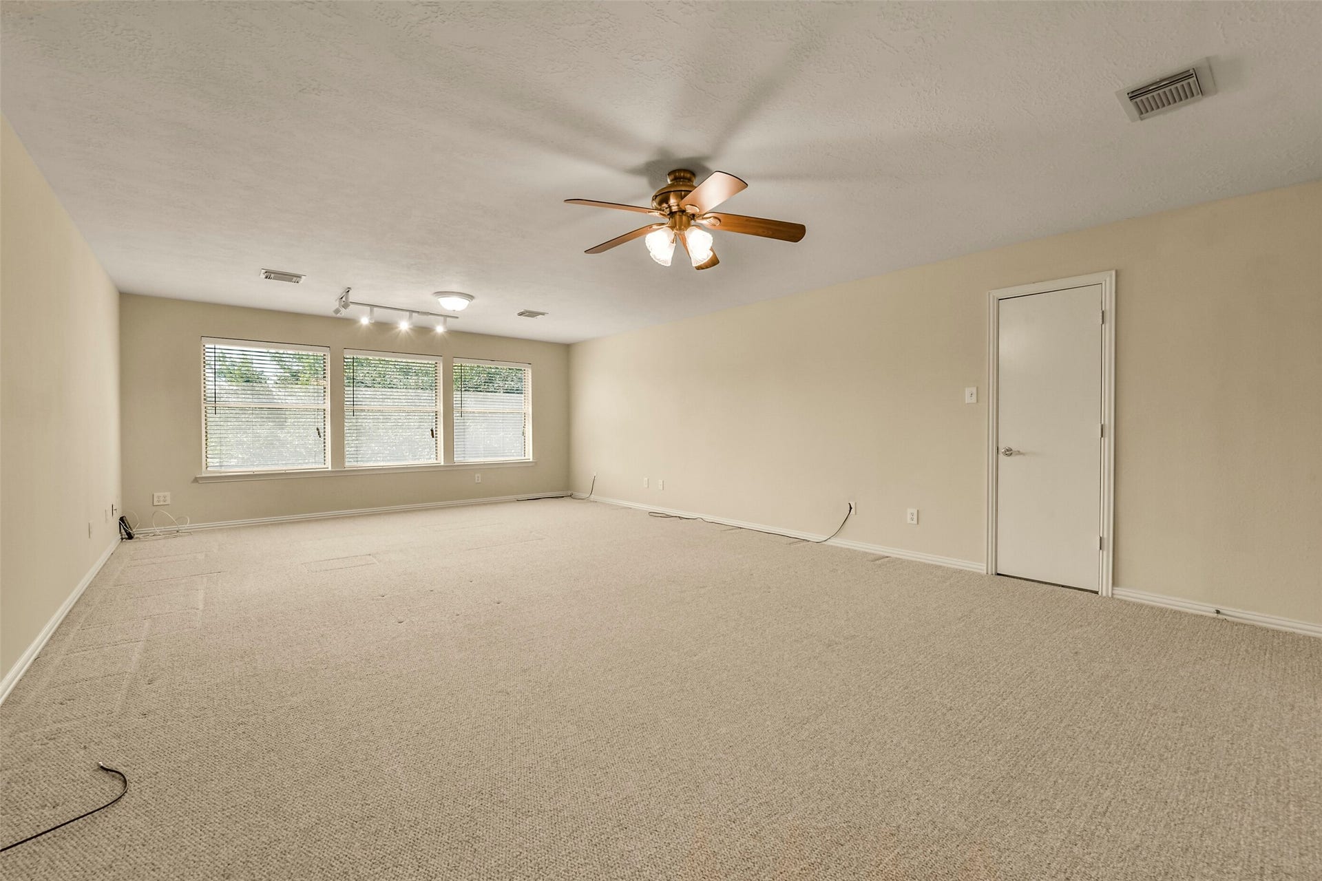 9902 Autumn Lake Trail, Pearland, TX 77584 Spacious carpeted gameroom with ample natural light from large windows, featuring a ceiling fan and neutral tones for versatile decor options.