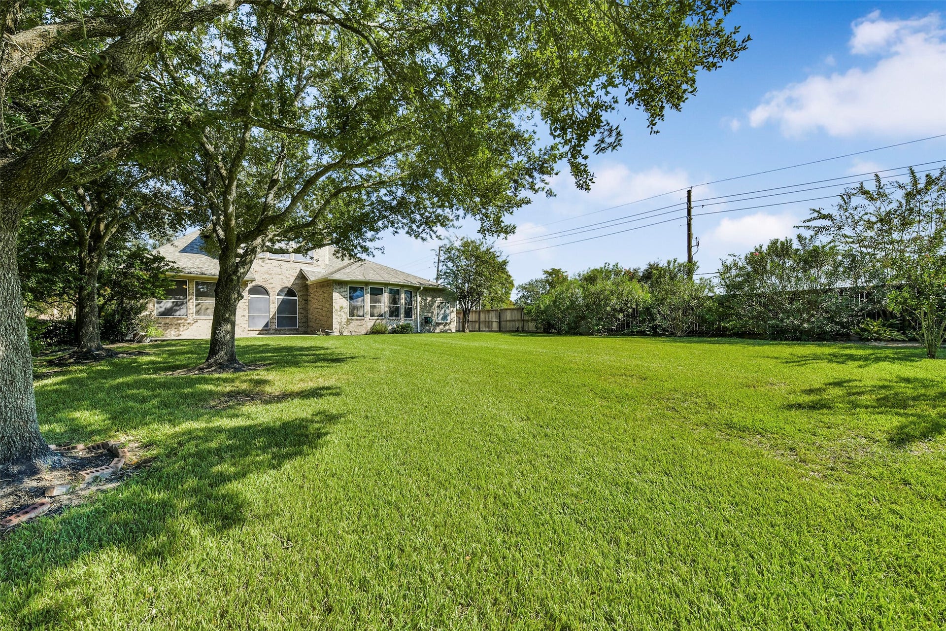 9902 Autumn Lake Trail, Pearland, TX 77584 Expansive backyard with lush green lawn and mature trees, offering ample space for outdoor activities and relaxation.
