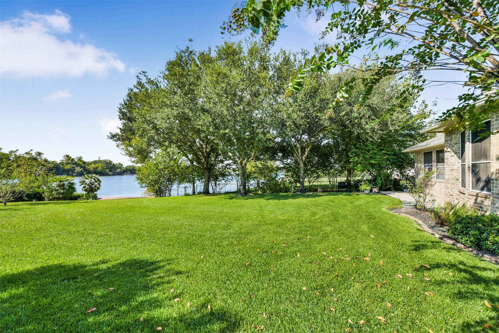 9902 Autumn Lake Trail, Pearland, TX 77584 Expansive backyard with lush greenery and a serene lake view, perfect for relaxation and outdoor activities.