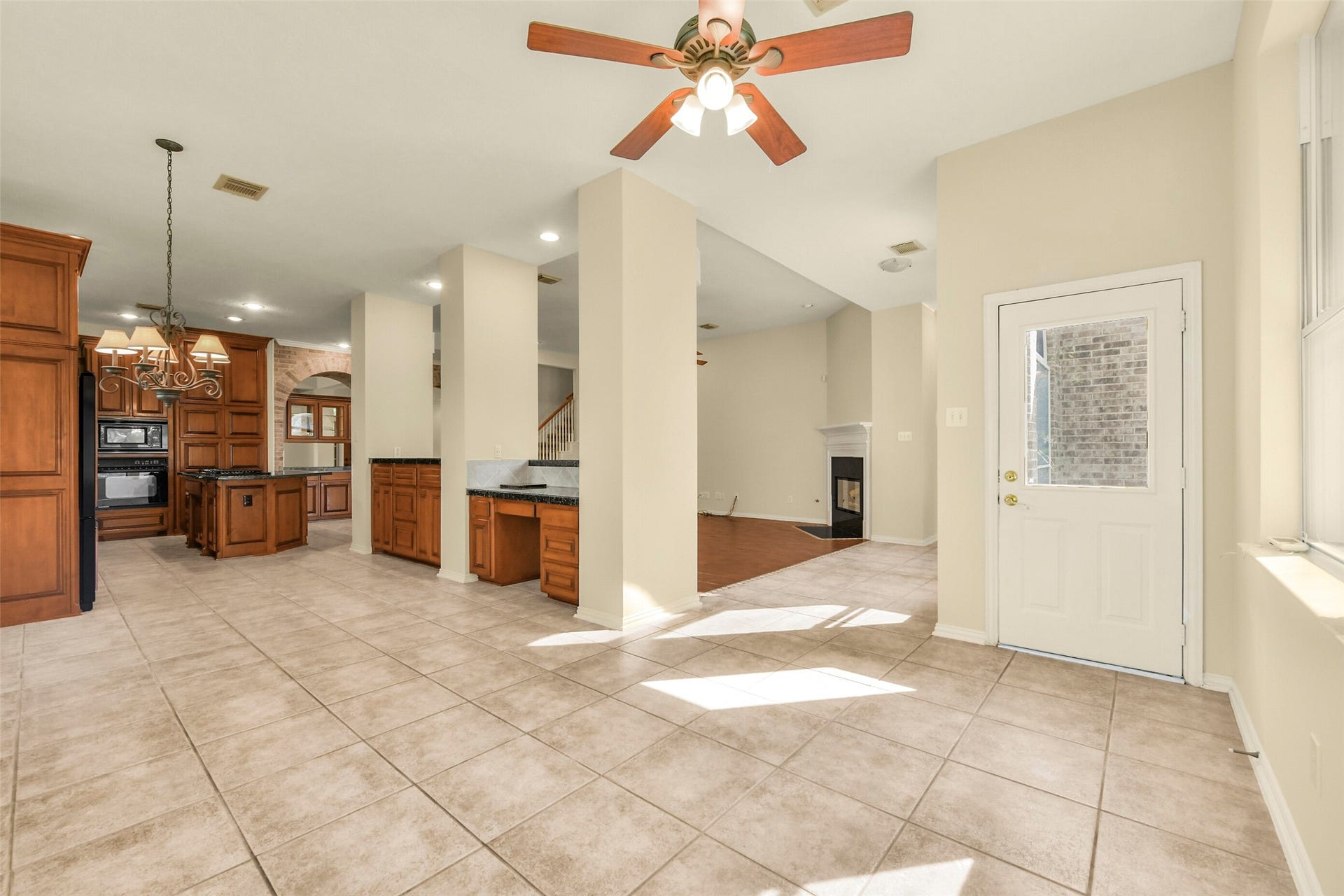 9902 Autumn Lake Trail, Pearland, TX 77584 Spacious open-concept living area featuring a gourmet kitchen with rich wooden cabinetry, granite countertops, and a central island, seamlessly flowing into a bright family room with a cozy fireplace.