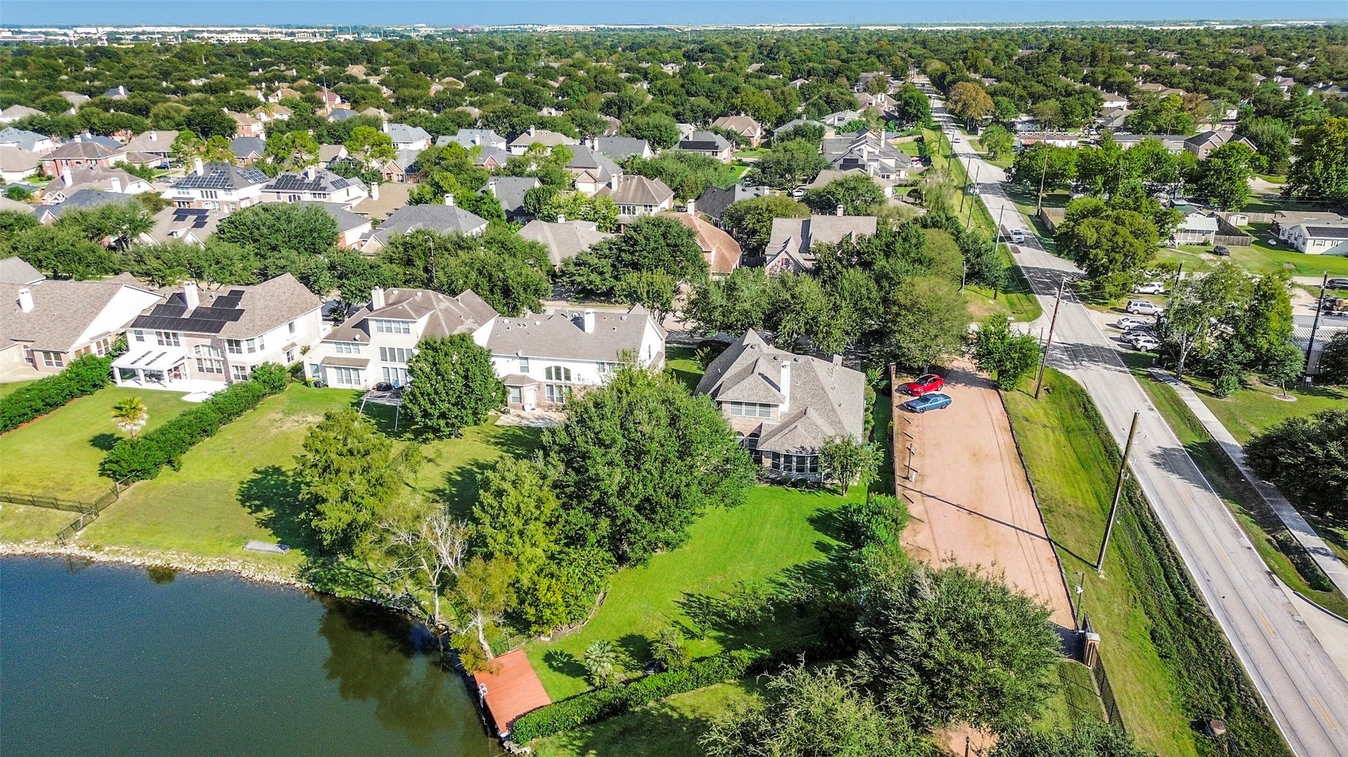 9902 Autumn Lake Trail, Pearland, TX 77584 Charming lakeside home nestled in a lush, tree-lined neighborhood, offering a serene escape with spacious green lawns and scenic views.