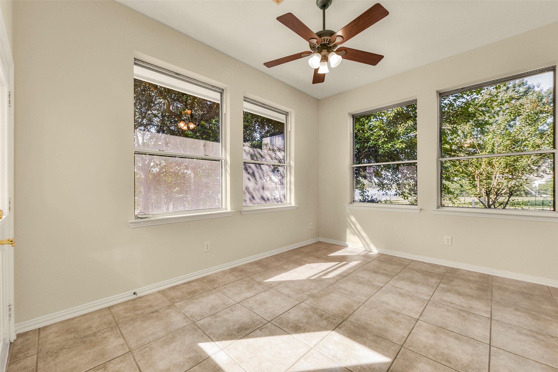 9902 Autumn Lake Trail, Pearland, TX 77584 Bright sunroom with large windows, neutral tile flooring, and a stylish ceiling fan, perfect for relaxation and enjoying garden views.