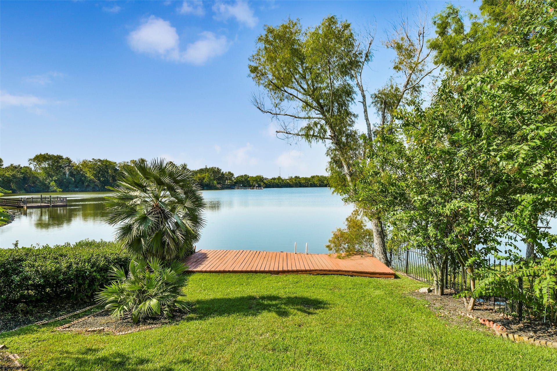 9902 Autumn Lake Trail, Pearland, TX 77584 Serene lakeside view with lush greenery, a private wooden dock, and tranquil waters perfect for relaxation and outdoor enjoyment.
