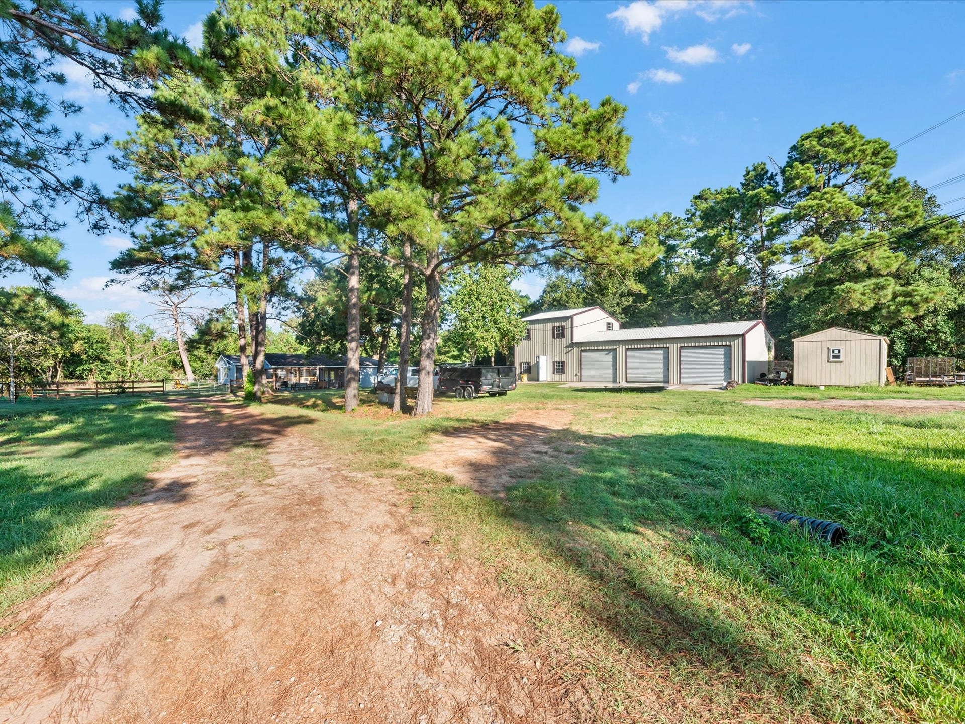 32403 Dobbin Huffsmith Road, Magnolia, TX 77354 Driveway leading to Structures 1 and 2. Structure 1 features a spacious 3-car garage with a 1-bedroom, 1-bath loft above. Structure 2 offers approximately 200 sq ft with a 1-bedroom layout.