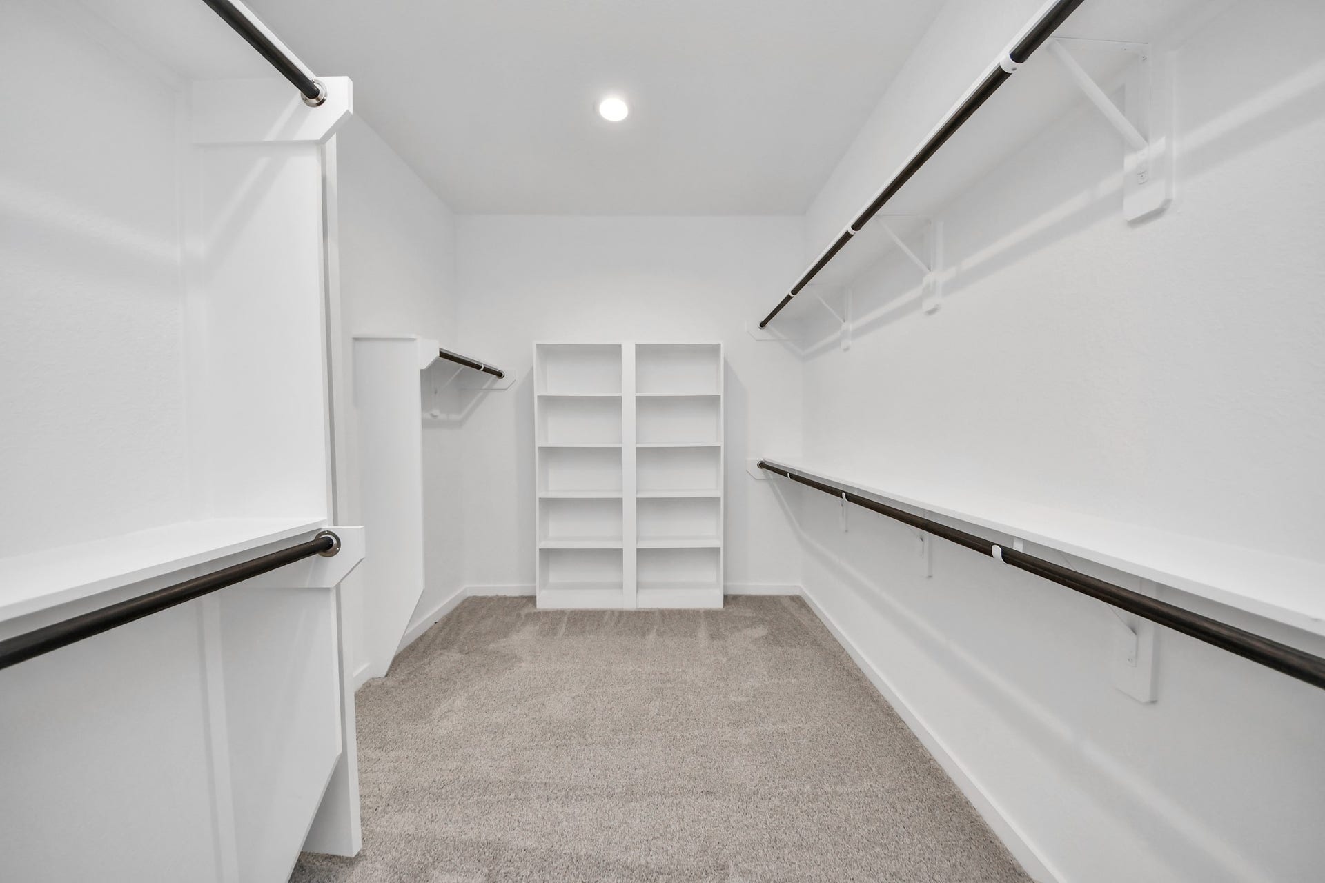 Walk-in closet that epitomizes luxury and practicality. This generously sized space features built-in shelving, offering abundant room for impeccable organization. High ceilings and recessed lighting create a bright and welcoming ambiance. Sample photo of completed home with similar floor plan. Actual colors and selections may vary.