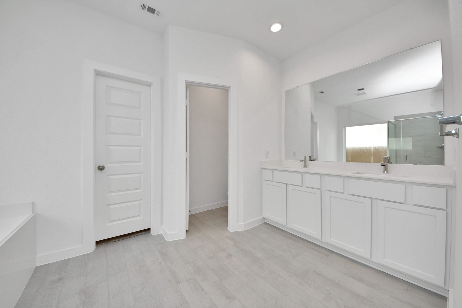 Elevate your daily routine at the elegant vanity, now equipped with double sinks, light countertops, modern hardware, and beautiful recessed lights. Sample photo of completed home with similar floor plan. Actual colors and selections may vary.