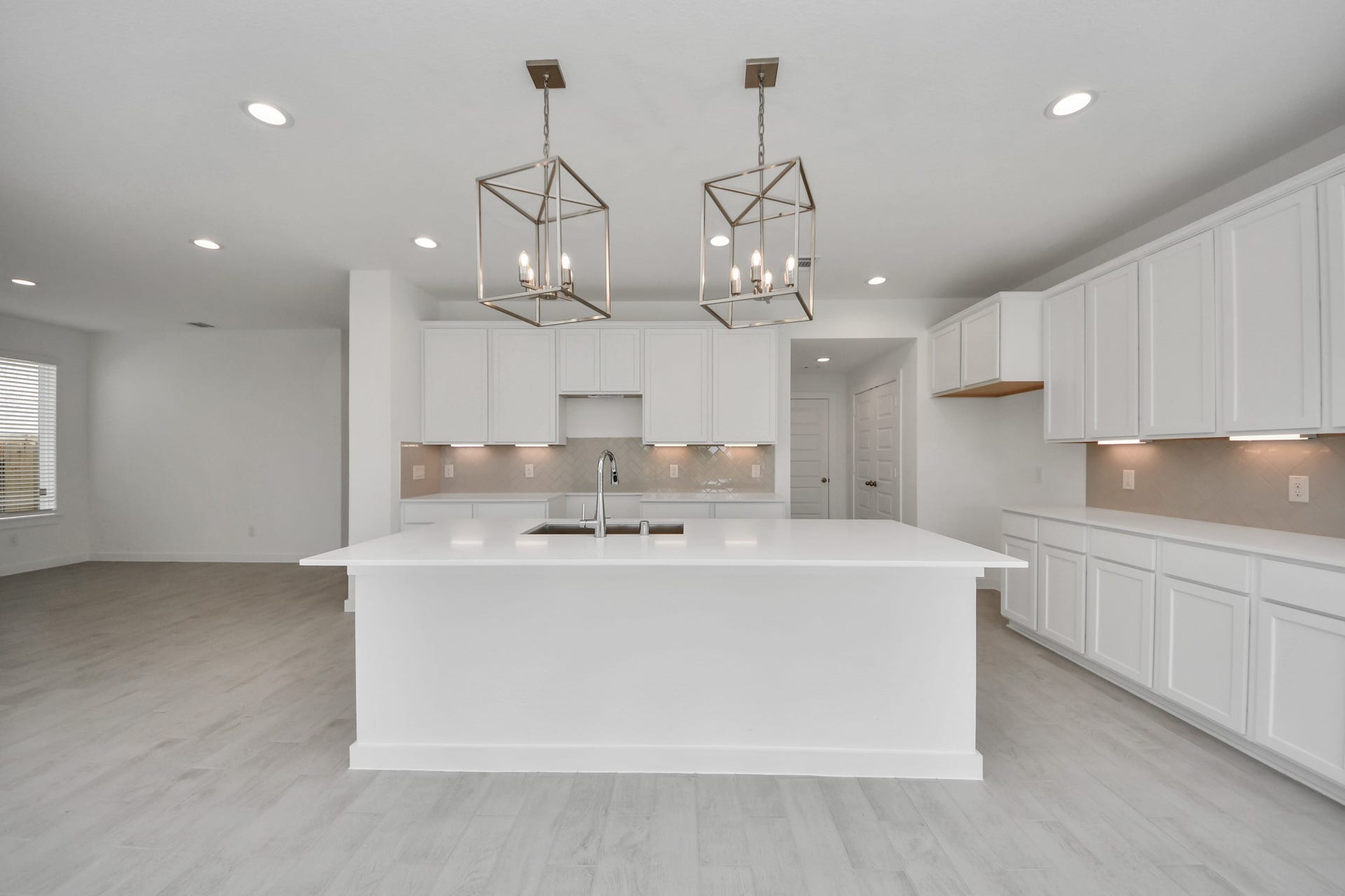 This kitchen is truly a chef's dream! This haven Boasts high ceilings, recessed & pendant lighting, stained wood cabinets, granite countertops, stainless steel appliances, a modern tile backsplash.  All of this overlooks your expansive family room, creating a perfect space for culinary delights and family gatherings. Sample photo of completed home with similar floor plan. Actual colors and selections may vary.