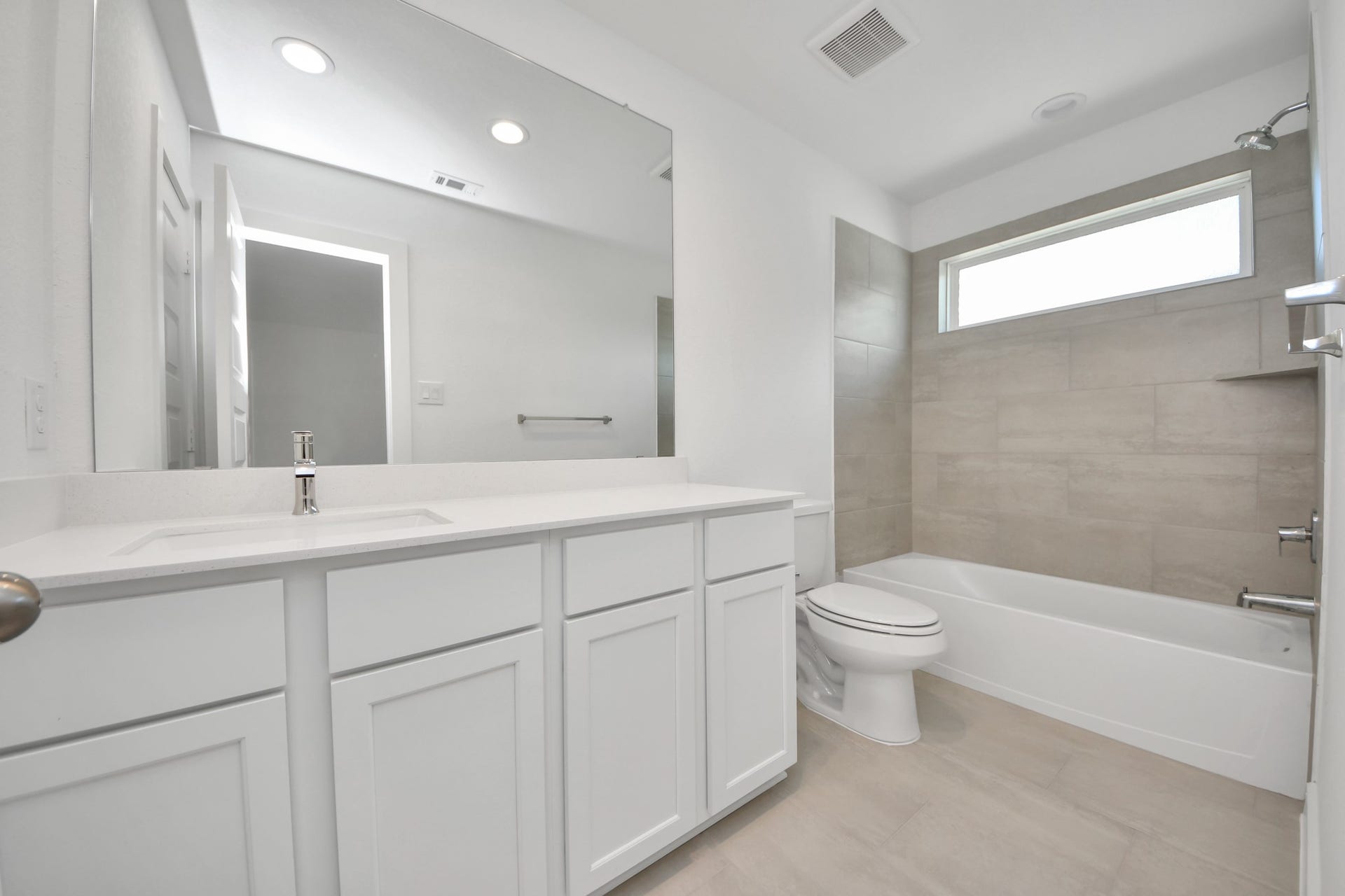 Secondary bath features tile flooring, bath/shower combo with tile surround, light stained wood cabinets, beautiful light countertop. Sample photo of completed home with similar floor plan. Actual colors and selections may vary.