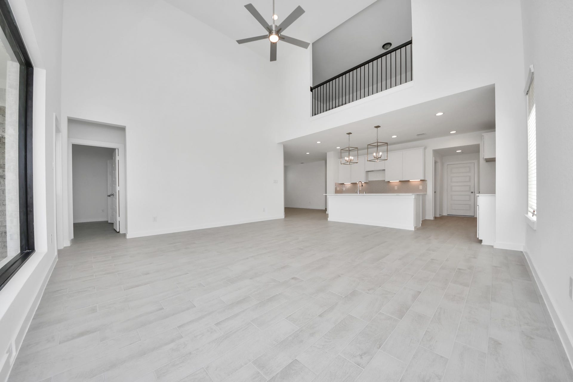 Relax and unwind in this inviting family room, illuminated by abundant natural light streaming in through tall windows, complemented by high ceilings and stunning flooring. Stay comfortable year-round with the gentle breeze from the ceiling fan, creating the perfect atmosphere for family gatherings. Sample photo of completed home with similar floor plan. Actual colors and selections may vary.