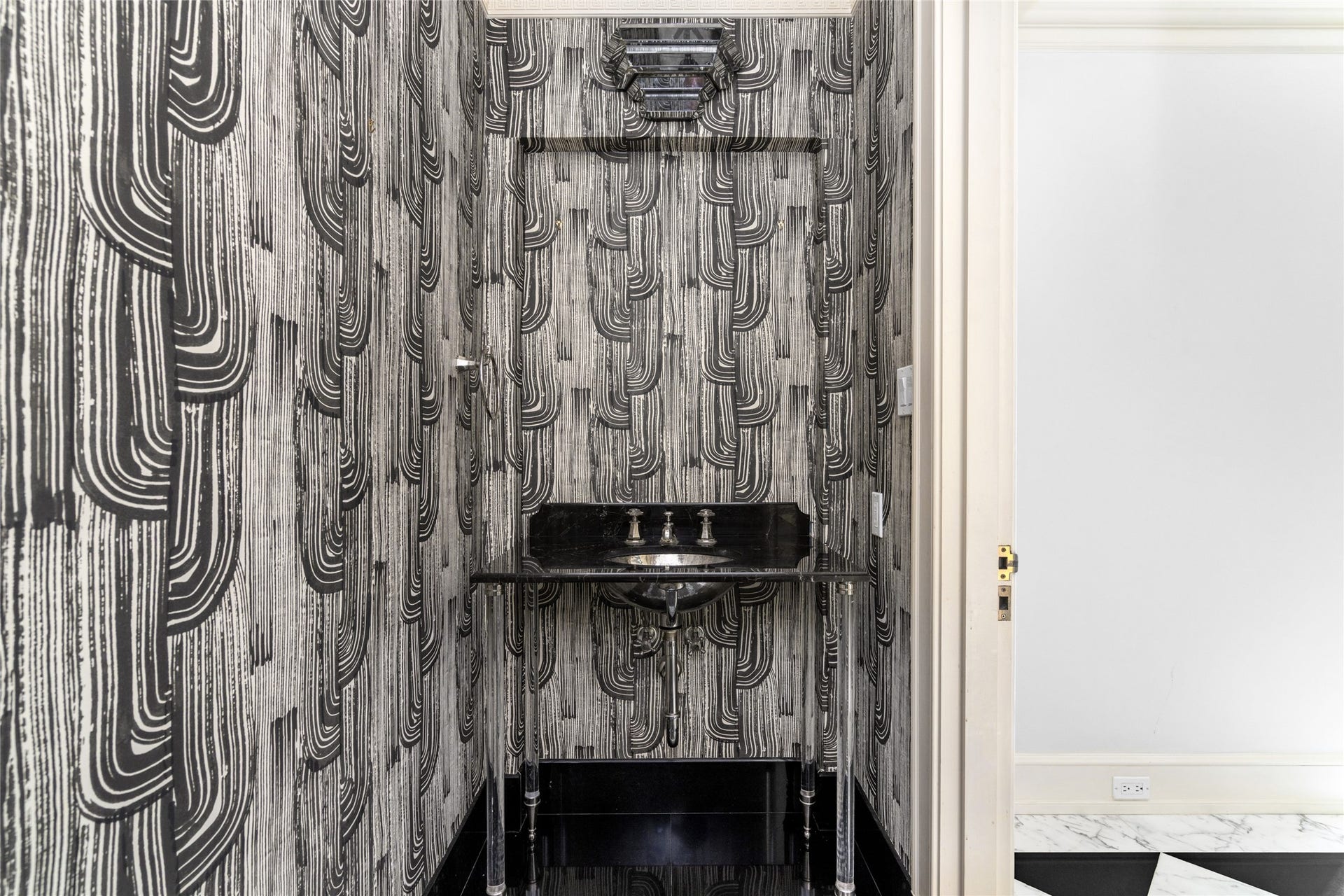 Powder room with bold patterned wallpaper, and a black console sink