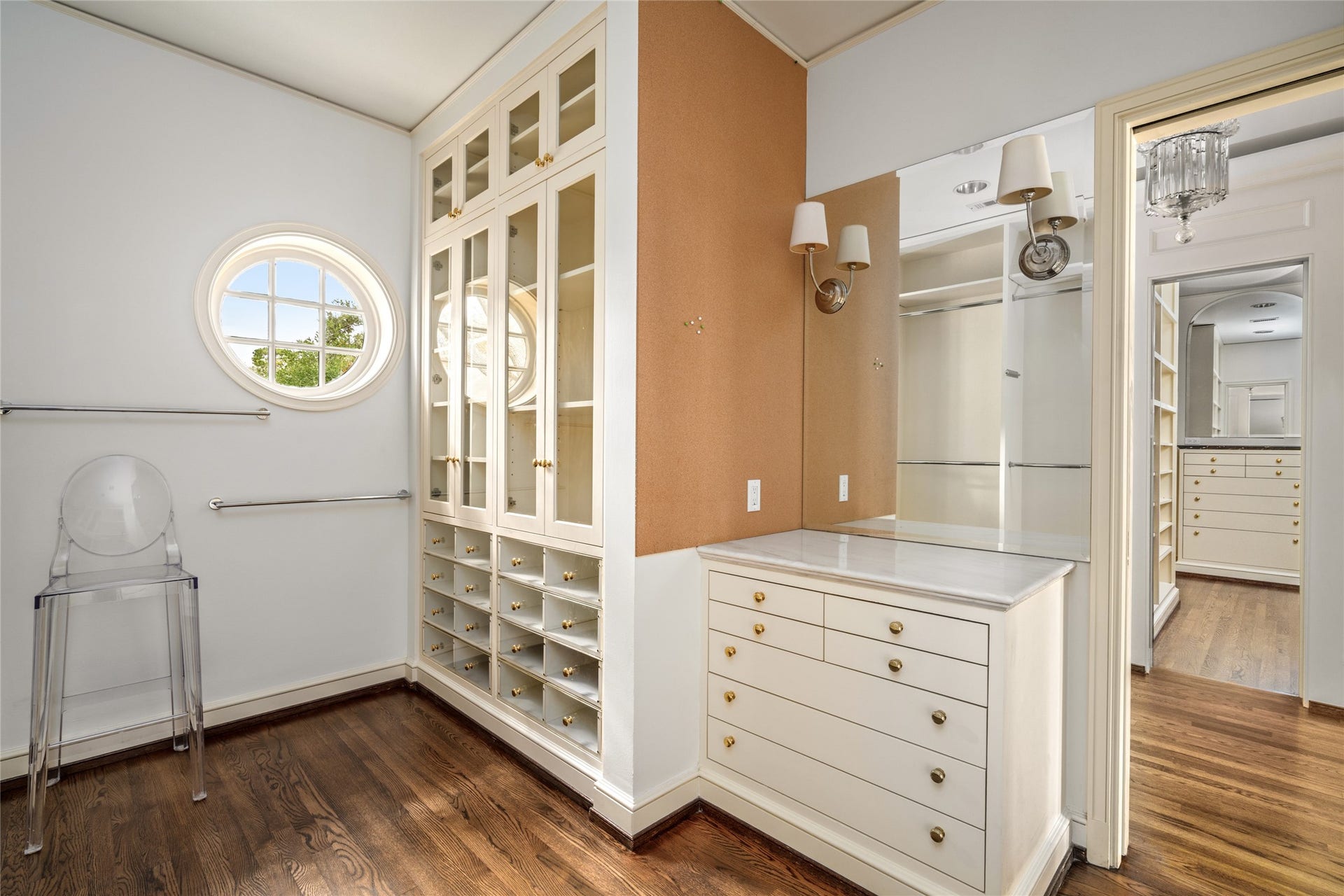 Primary suite dressing area with glass front cabinetry, built in drawers, shoe storage, and jewelry cabinet